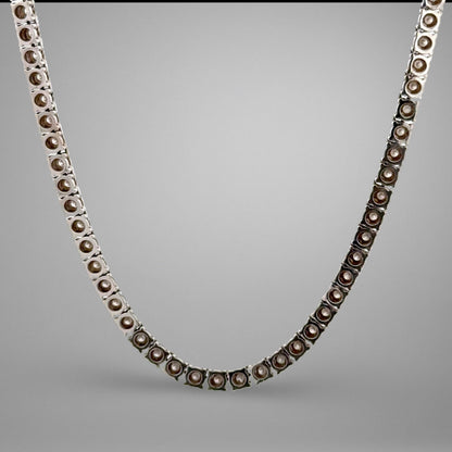 Silver necklace with brown beads on a gray background