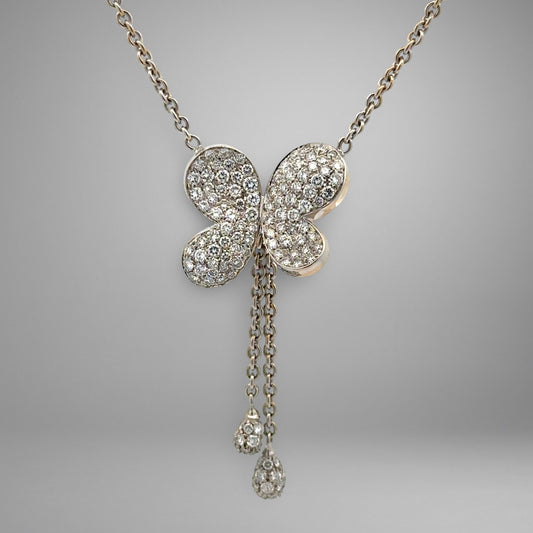 Butterfly-shaped diamond pendant on a chain against a gray background