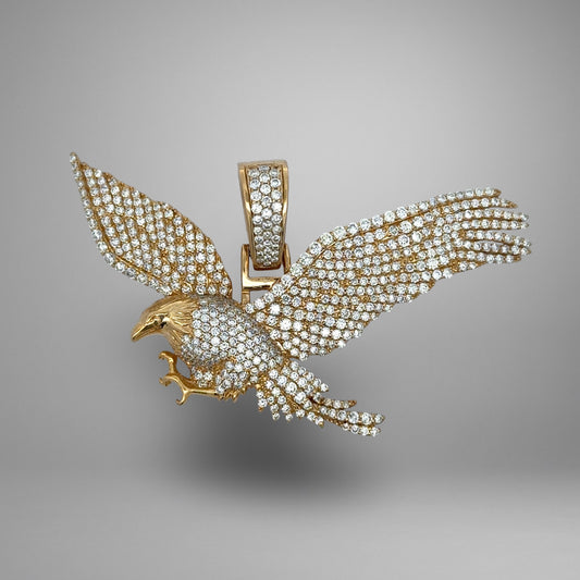 Gold and diamond eagle pendant on a gray background