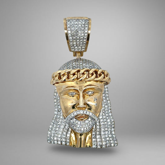 Gold pendant shaped like a face with a crown of thorns on a gray background
