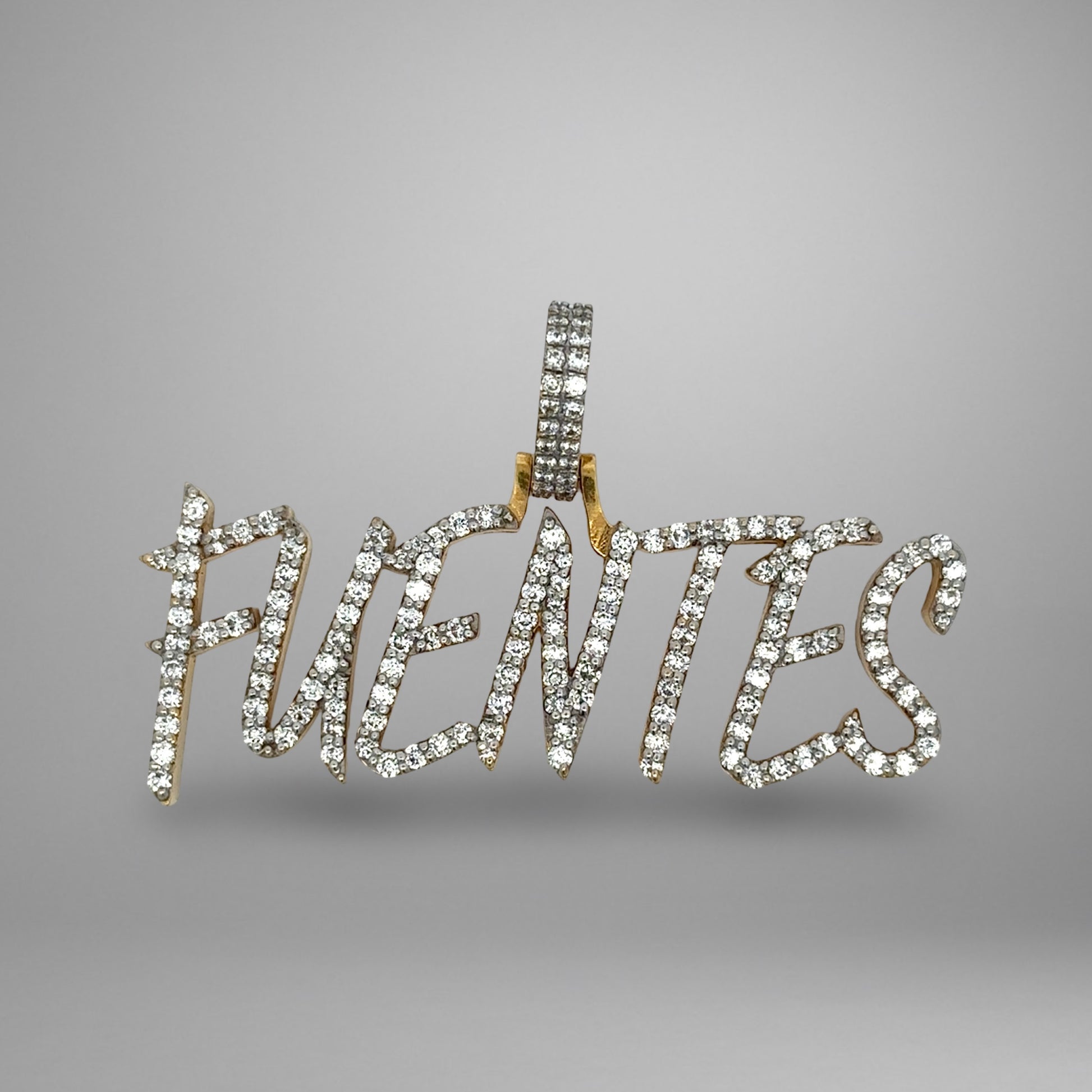 Diamond-studded pendant with the word 'FUENTES on a gray background