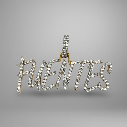 Diamond-studded pendant with the word 'FUENTES on a gray background