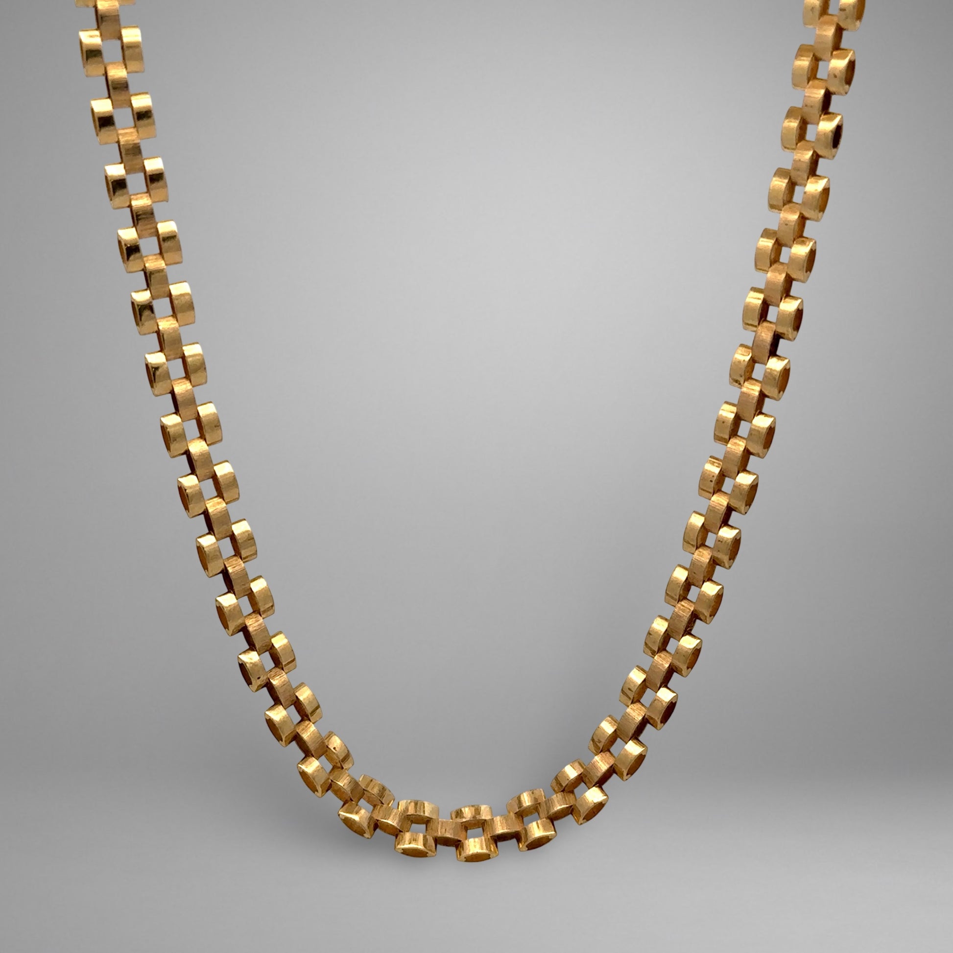 Gold chain necklace on a gray background