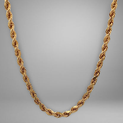 Gold rope chain necklace on a gray background