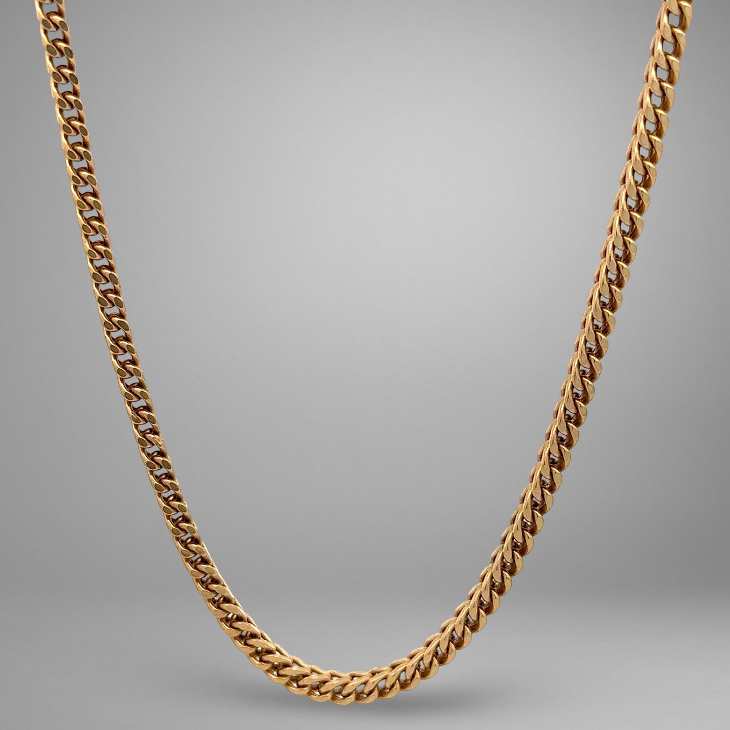 Gold chain necklace on a gray background