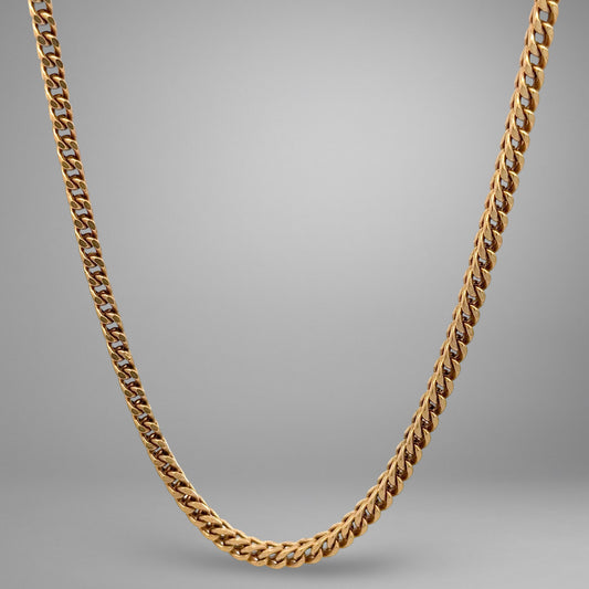 Gold chain necklace on a gray background