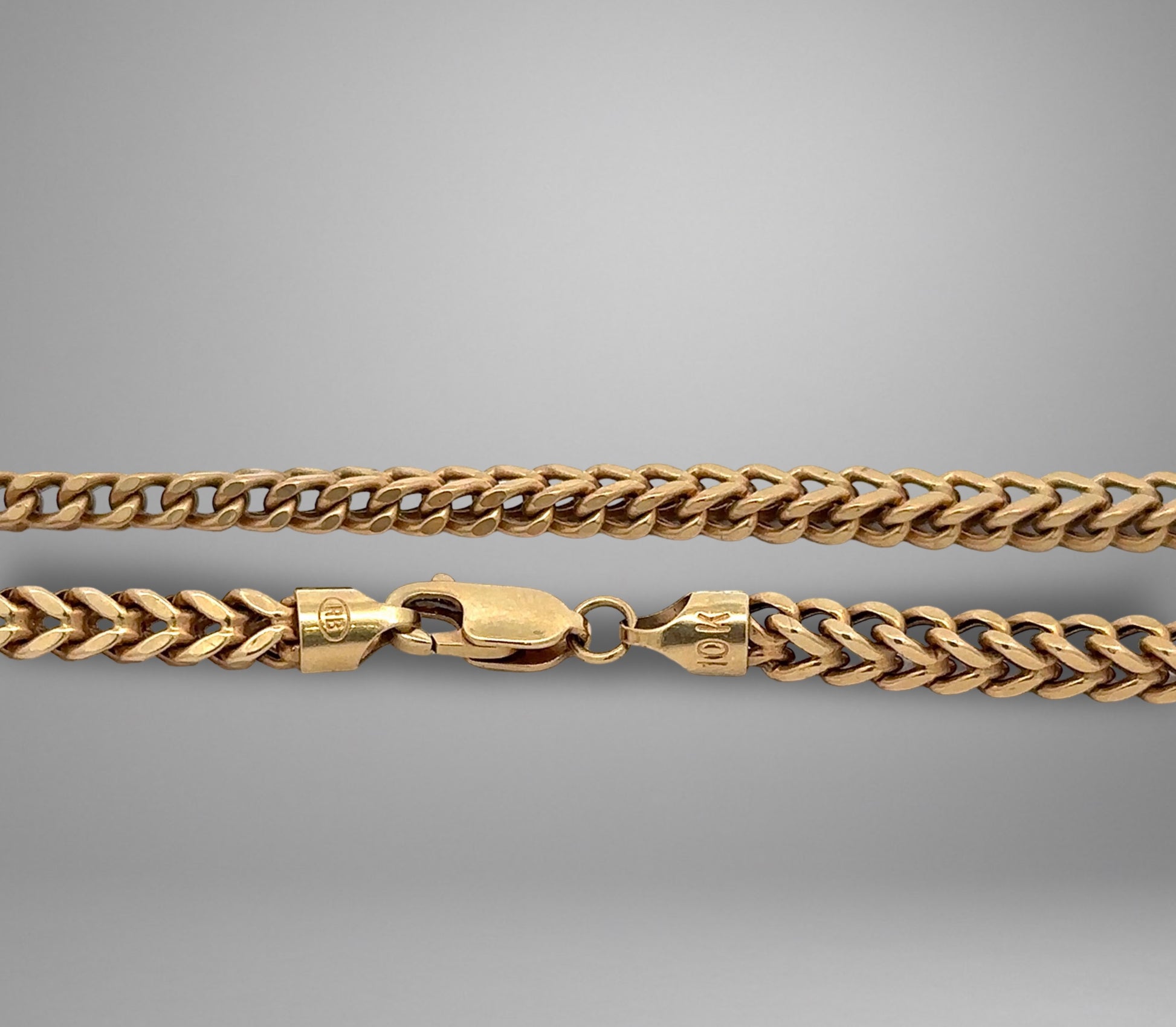 Gold chain necklace on a gray background