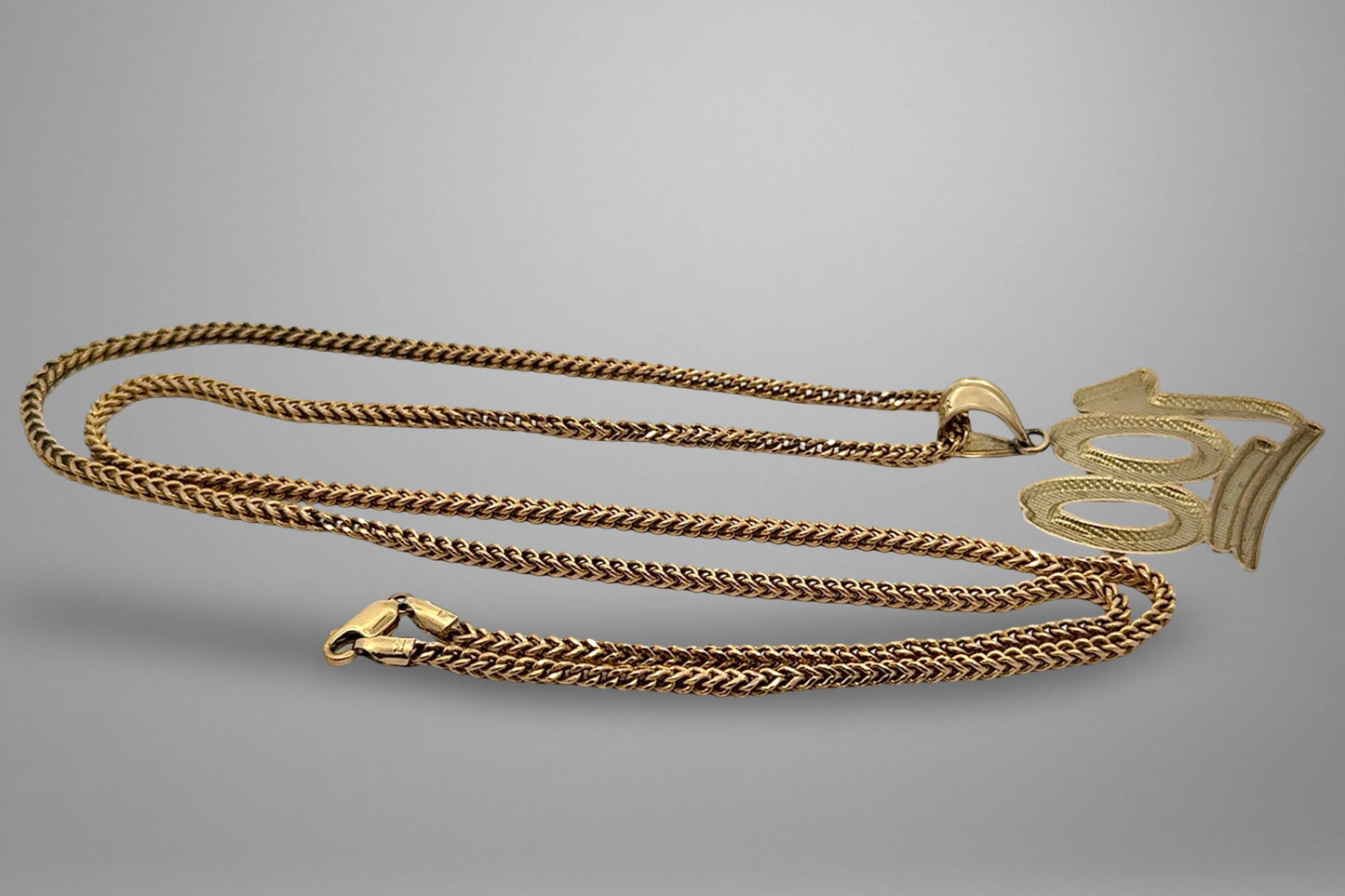 Gold chain necklace on a gray background