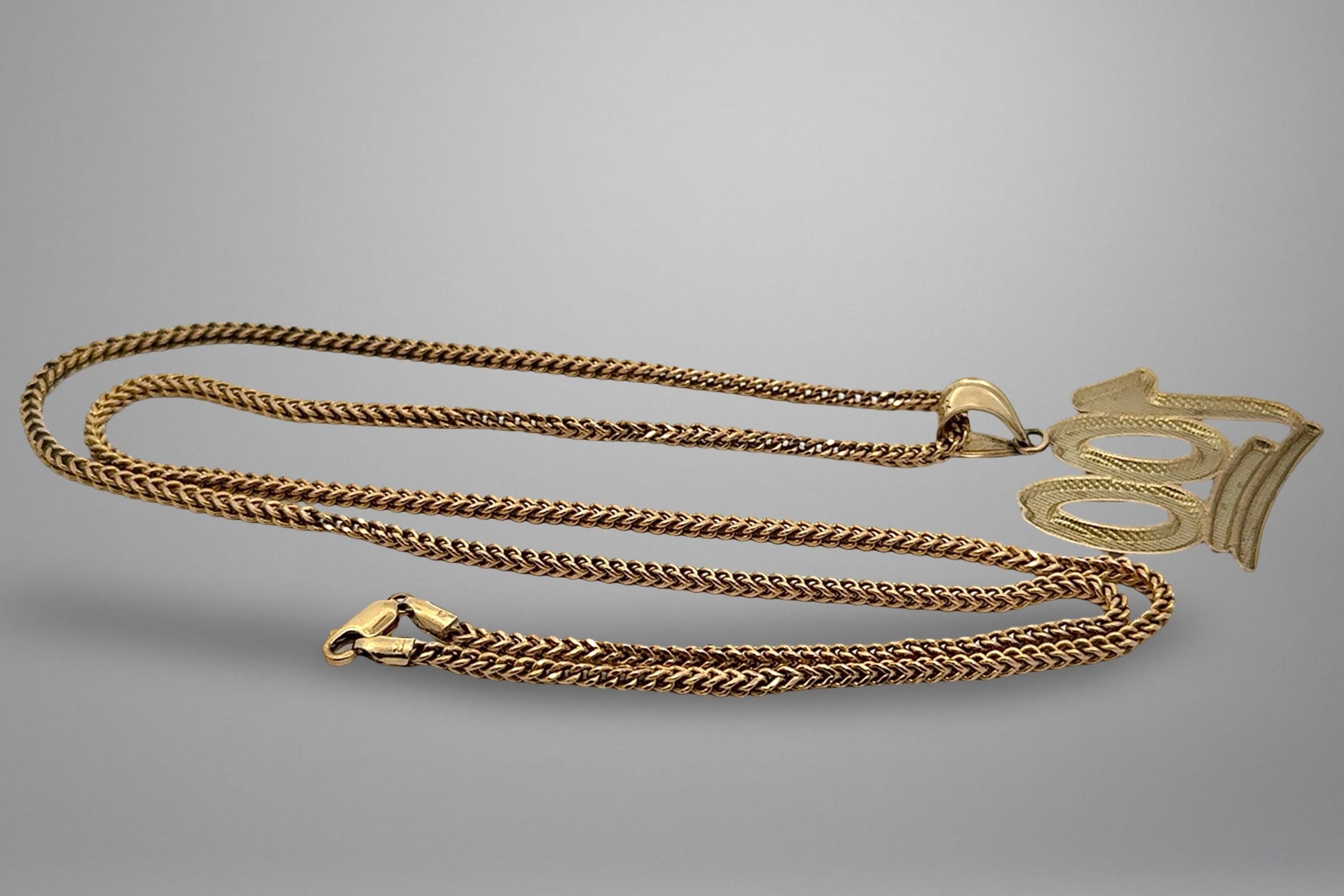 Gold chain necklace on a gray background