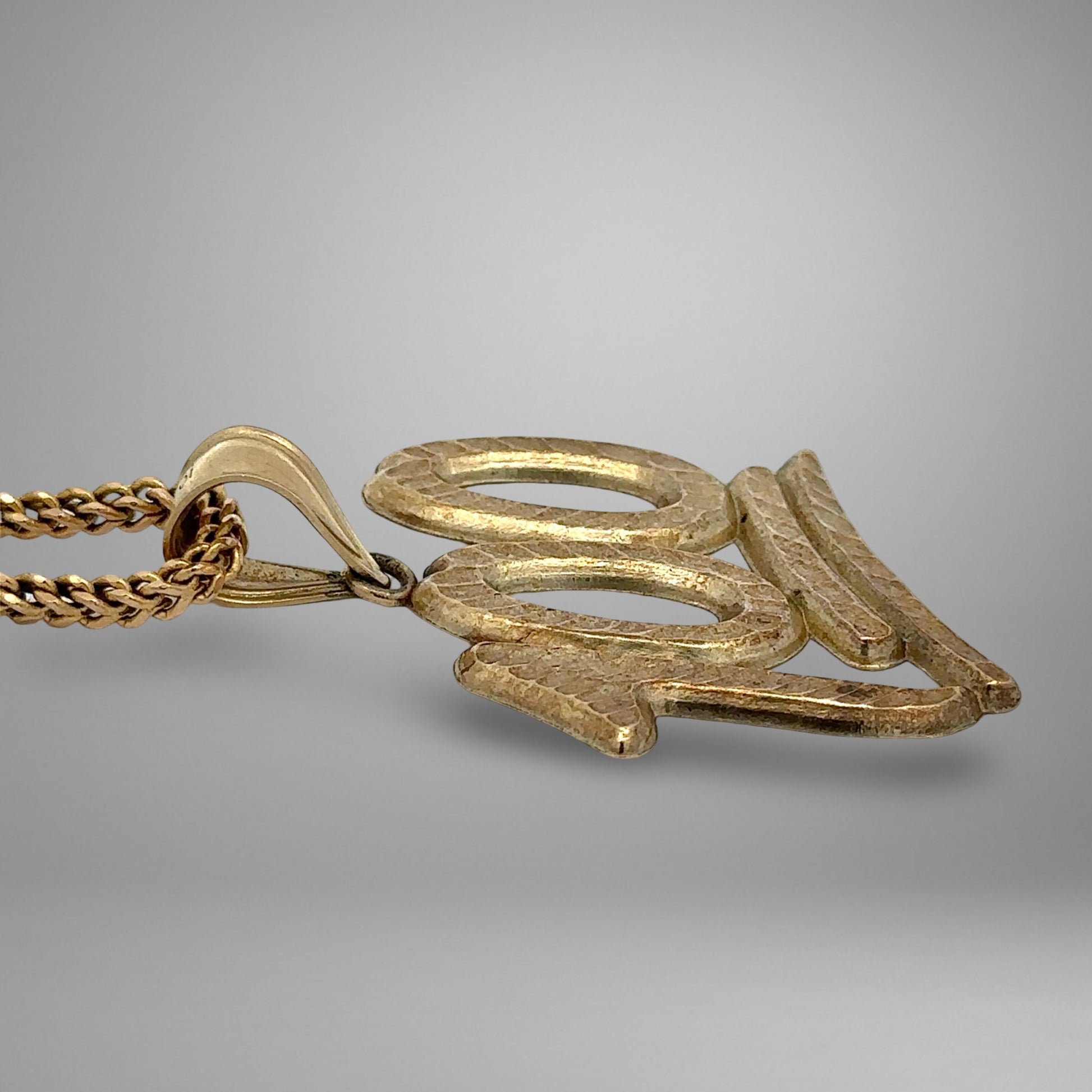 Gold necklace with a pendant on a gray background