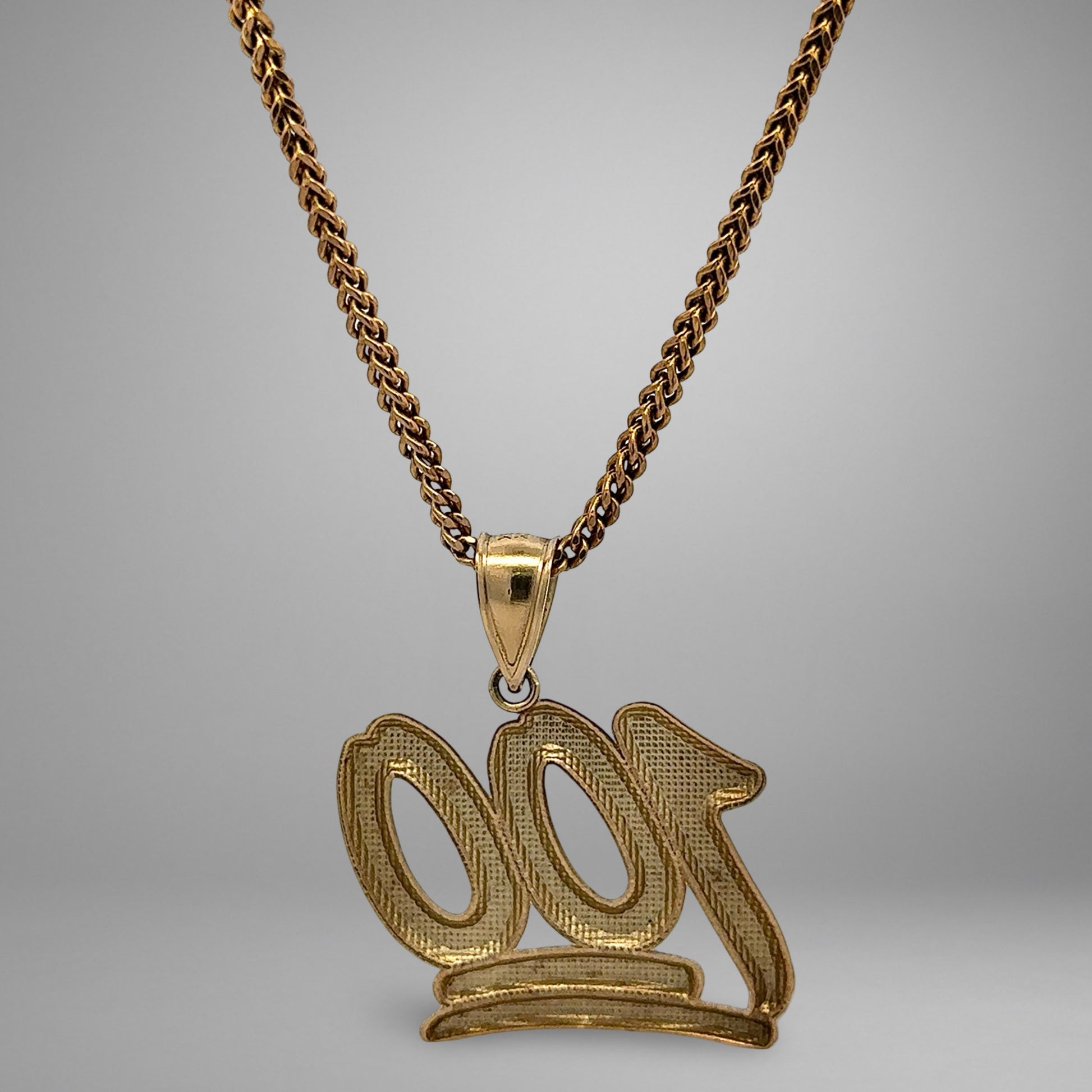 Gold '100' pendant on a chain against a gray background
