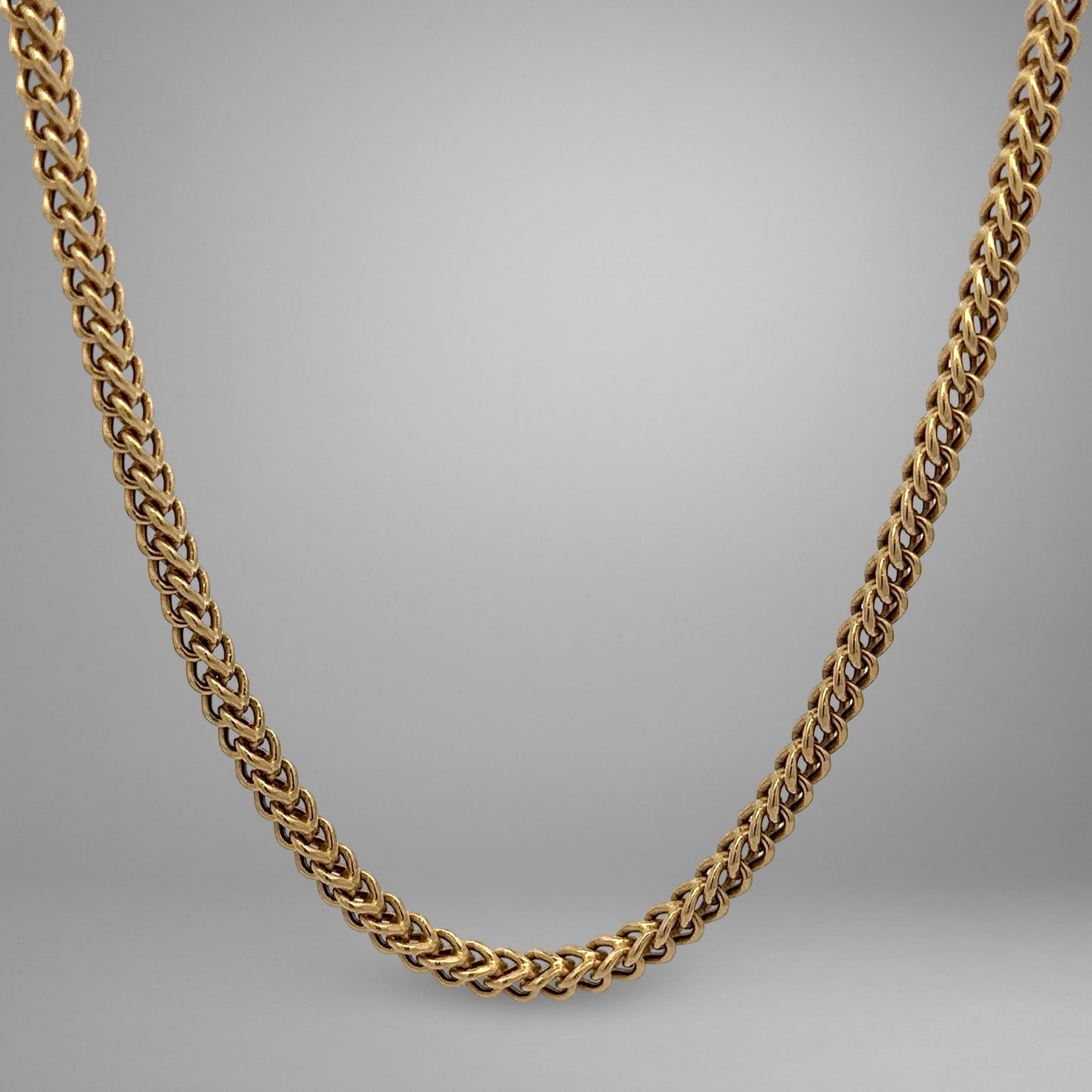 Gold chain necklace on a gray background