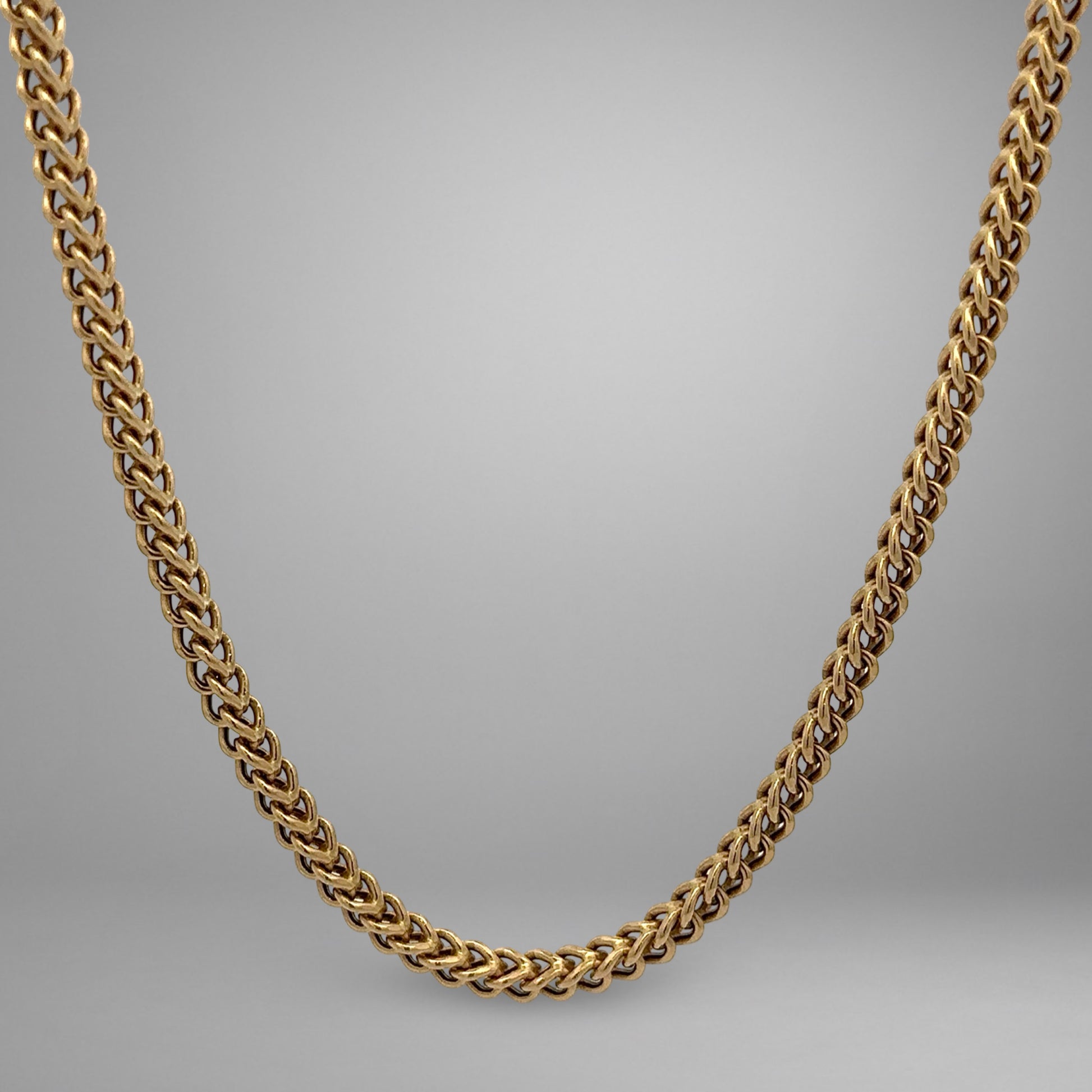 Gold chain necklace on a gray background