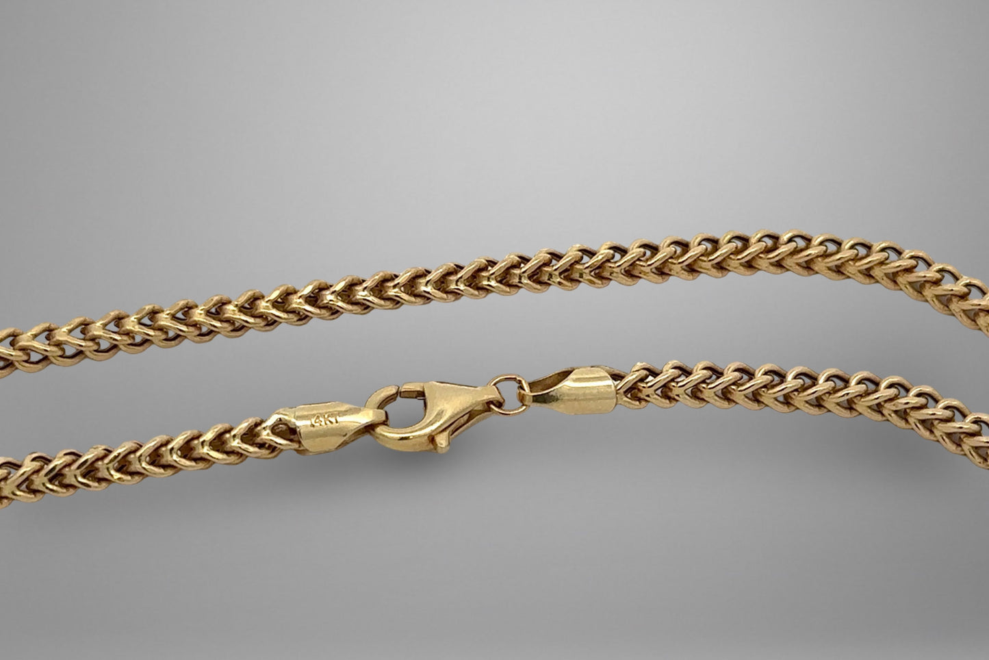 Gold chain necklace on a gray background