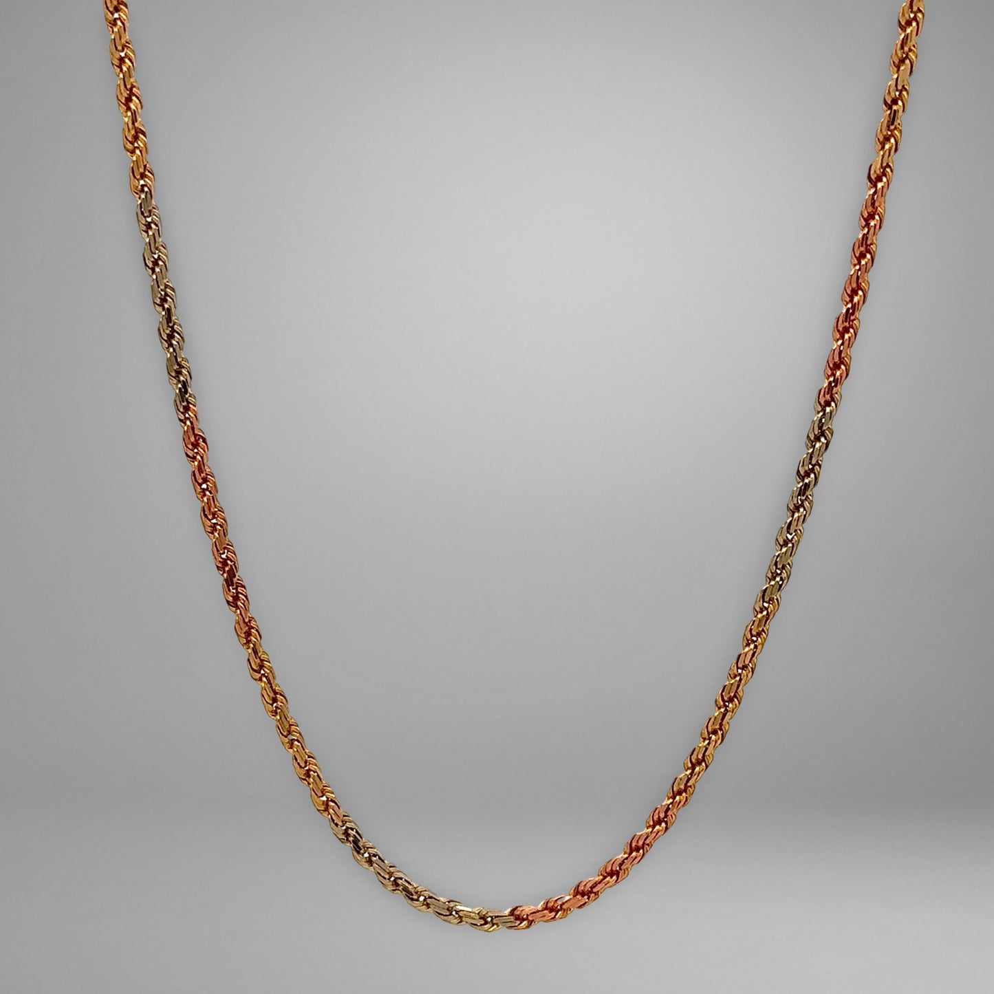 Yellow gold, rose gold, & white gold rope chain on grey background