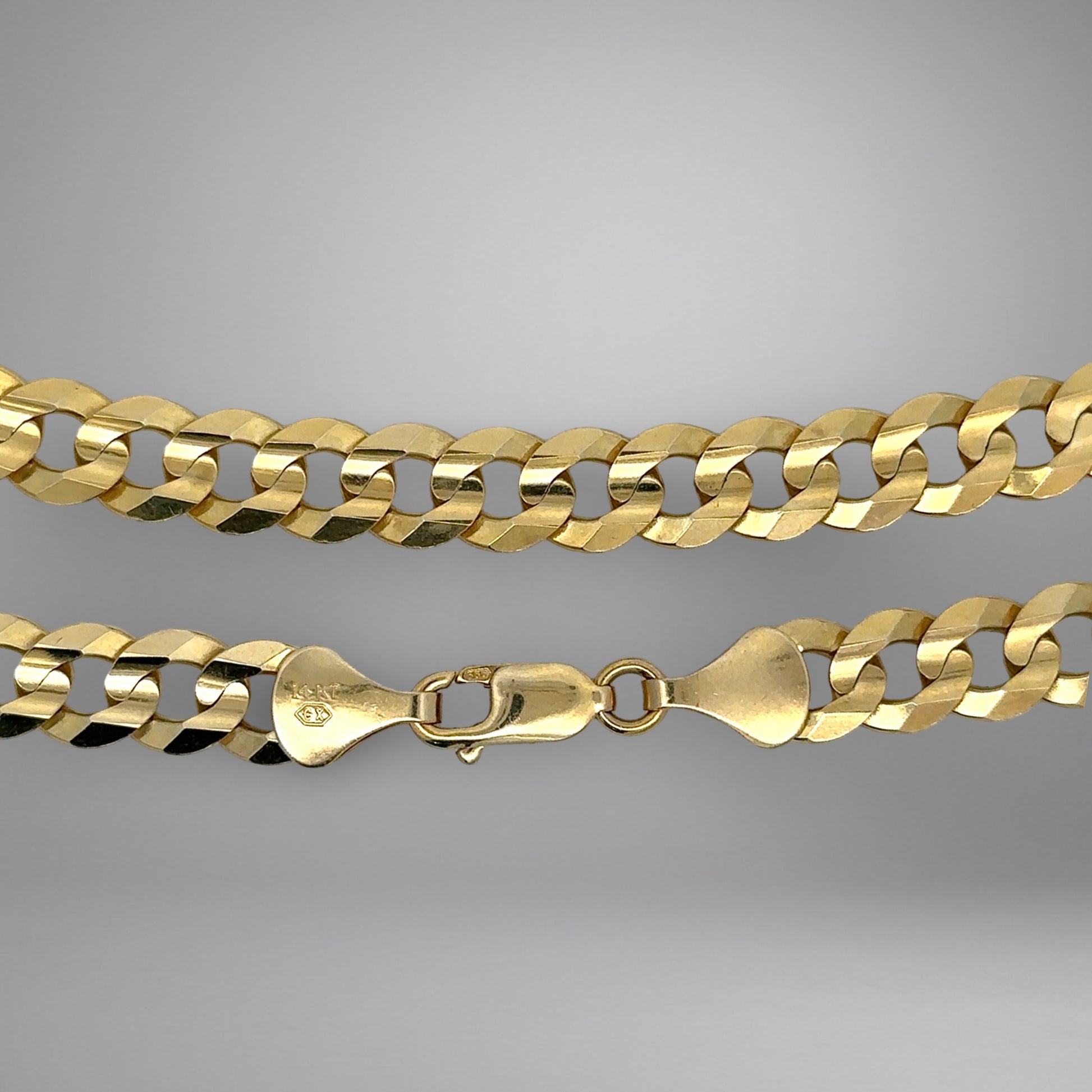 Gold chain necklace on a gray background