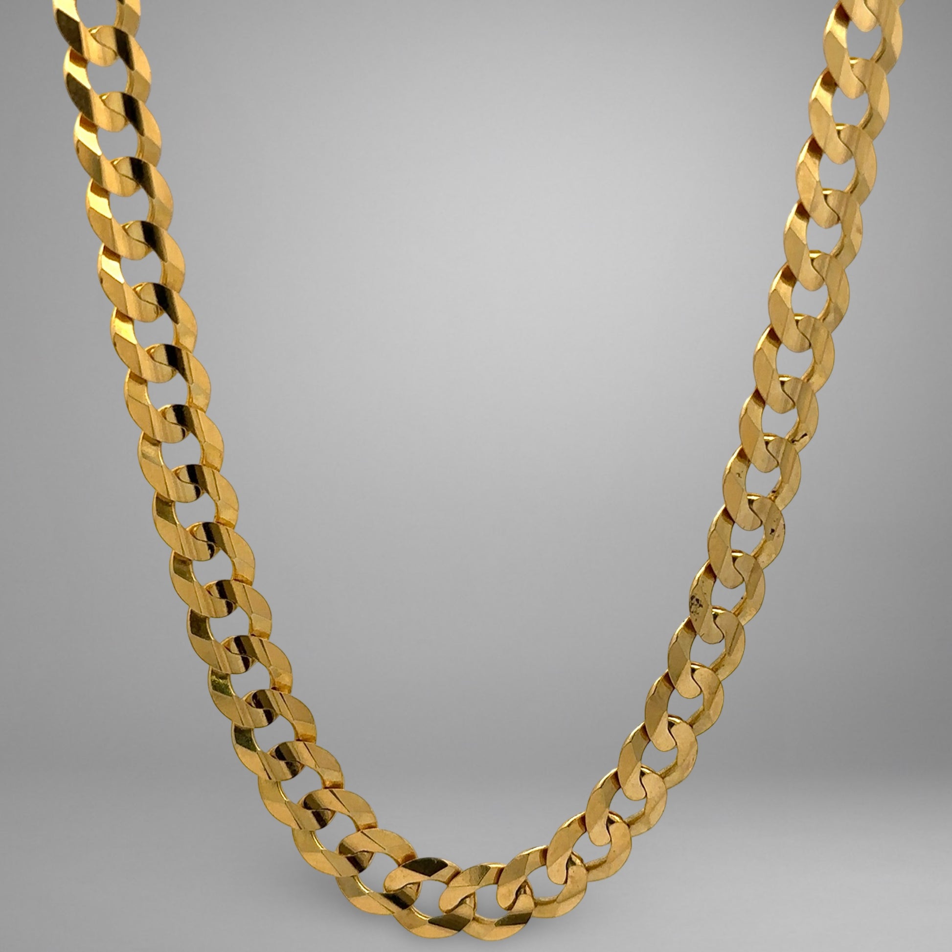 Gold chain necklace on a gray background