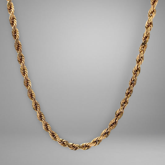 Gold rope chain necklace on a gray background