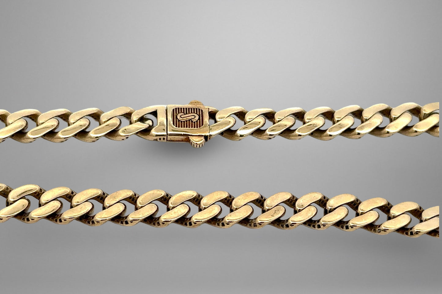 Gold chain bracelet on a gray background