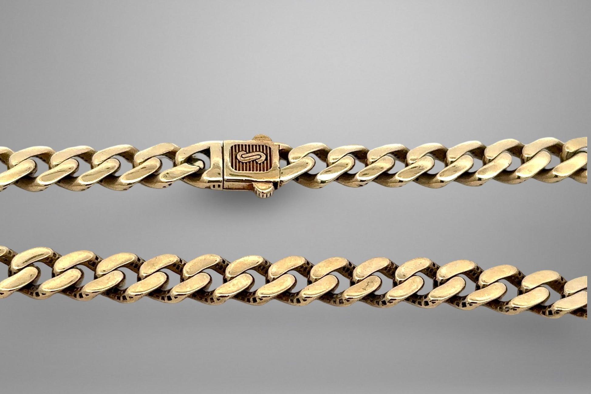 Gold chain bracelet on a gray background