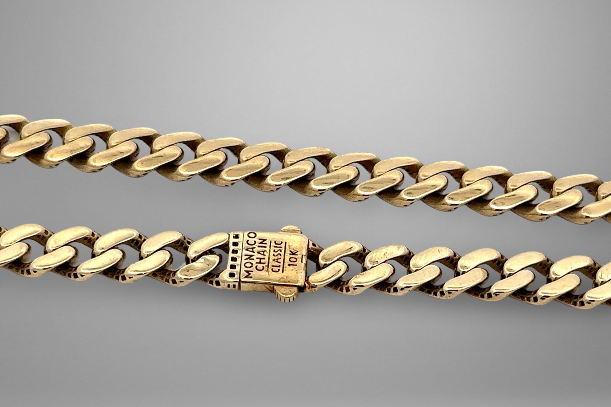 Gold chain bracelet on a gray background