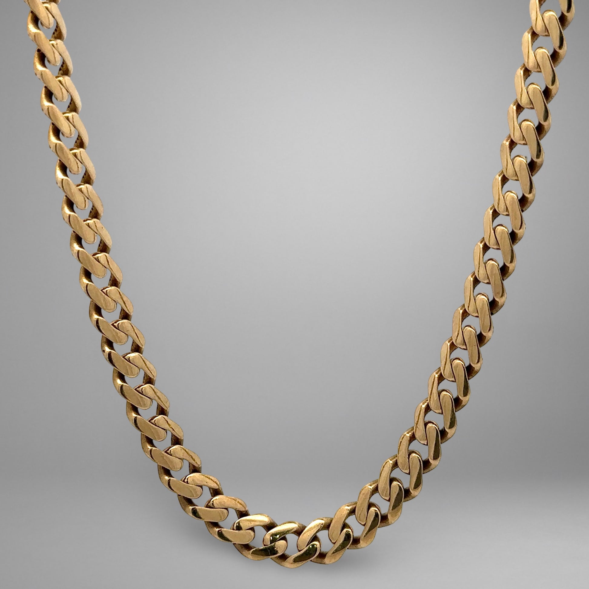 Gold chain necklace on a gray background