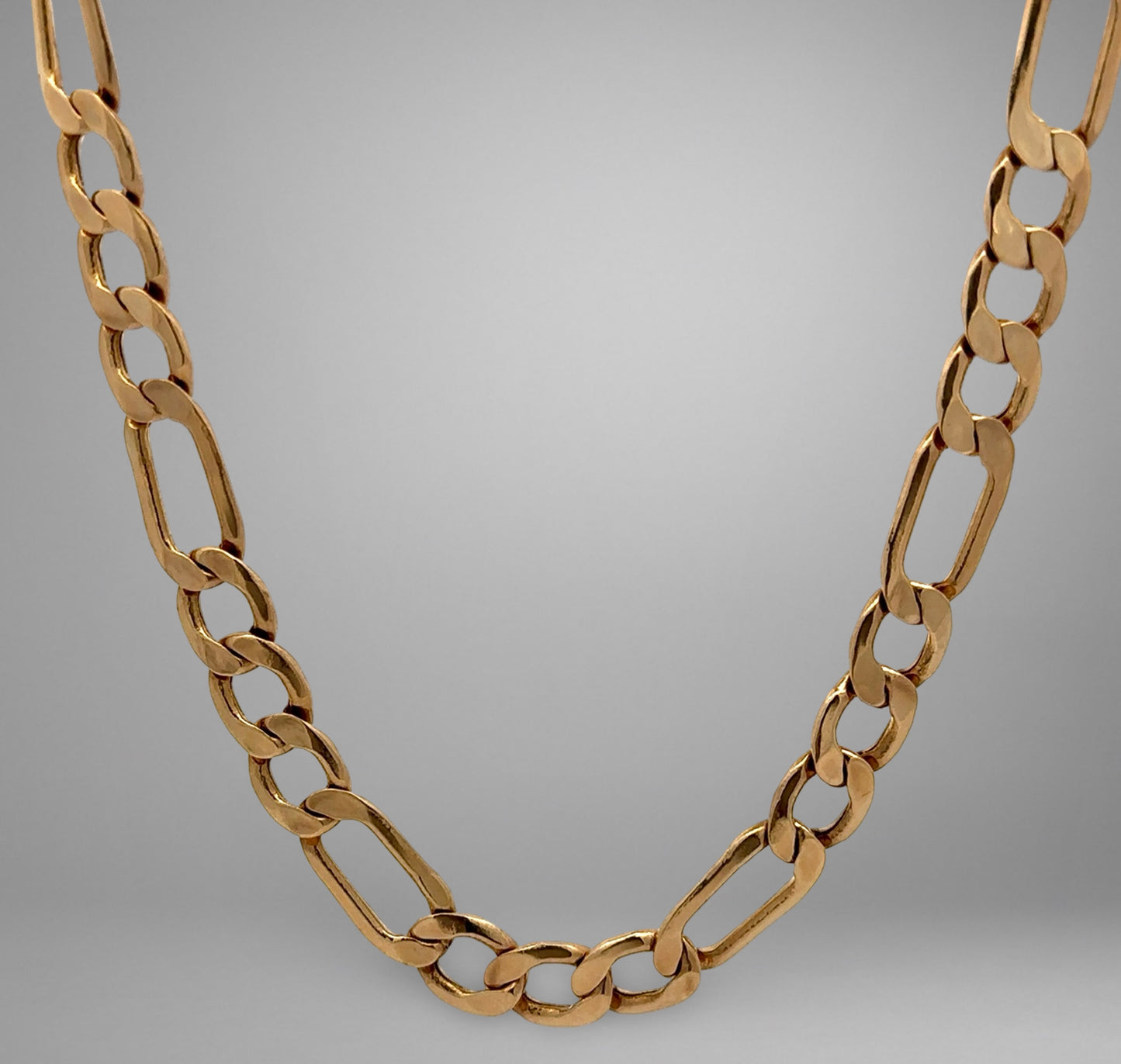 Gold chain necklace on a gray background