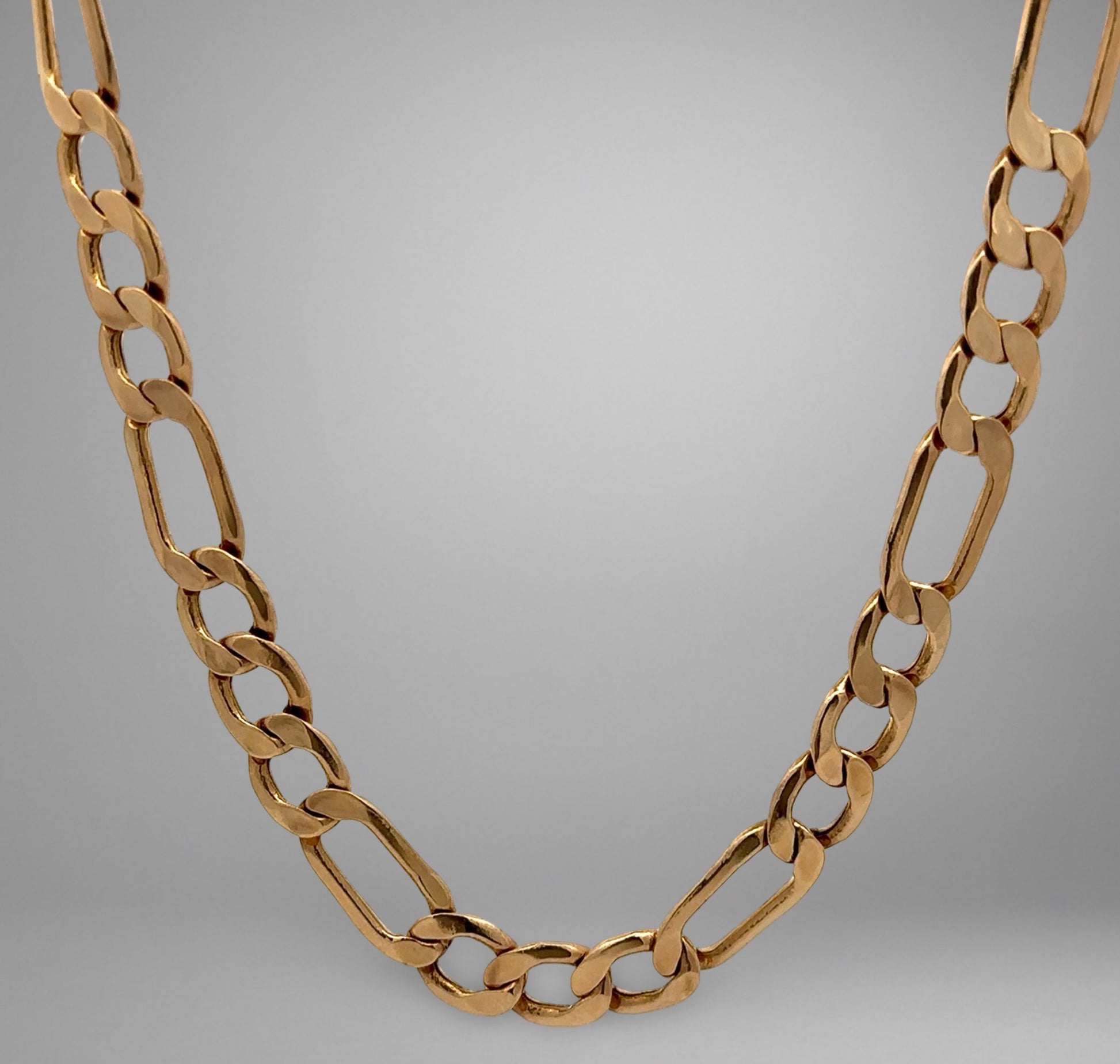 Gold chain necklace on a gray background