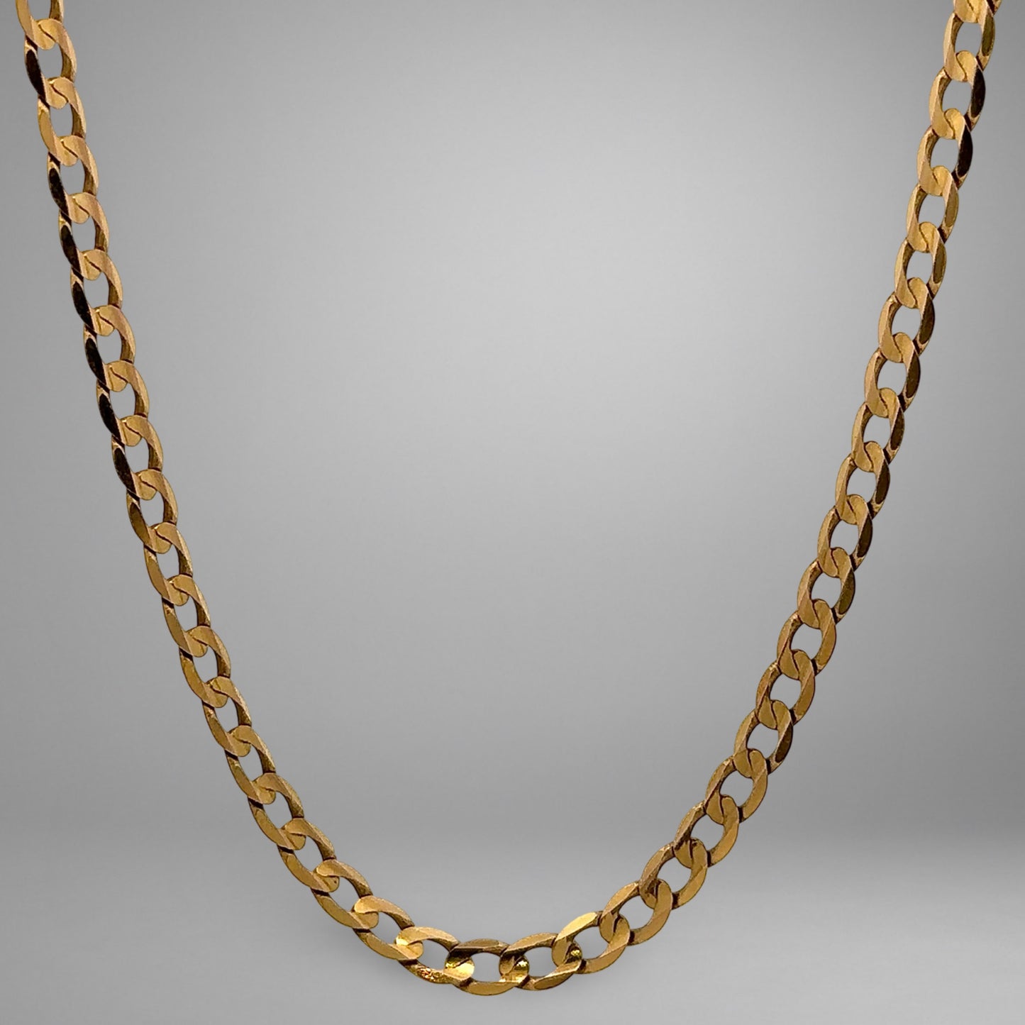 Gold chain necklace on a gray background
