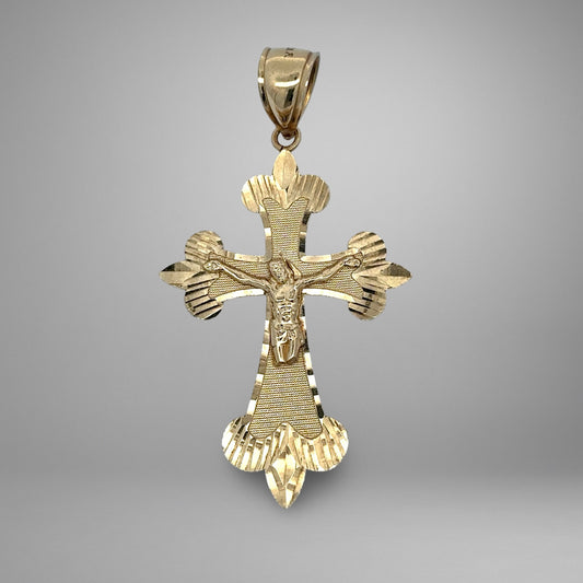 Gold cross pendant with detailed design on a gray background