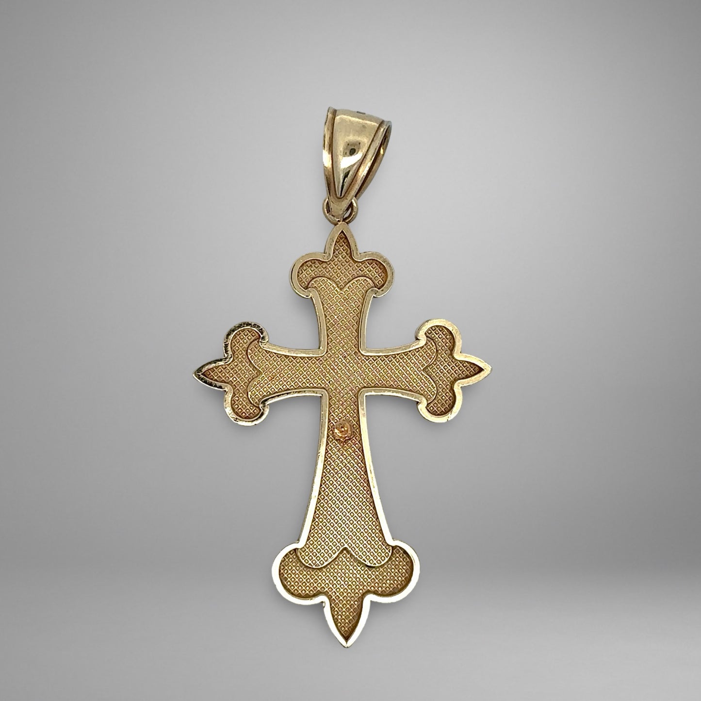 Gold cross pendant on a gray background