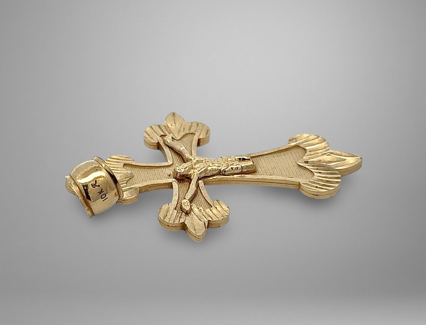 Gold cross pendant on a gray background