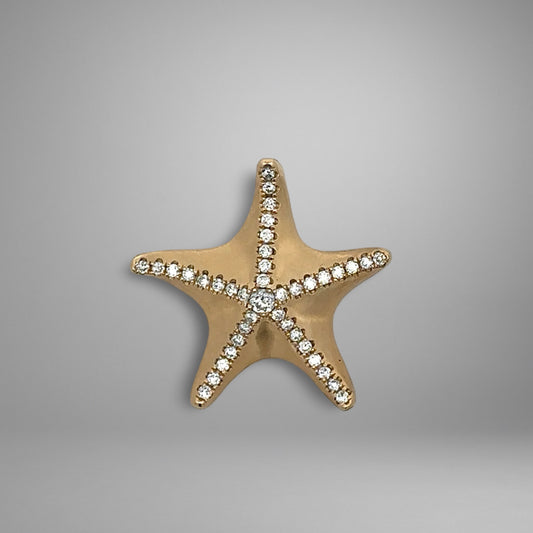 Gold starfish pendant with embedded diamonds on a gray background