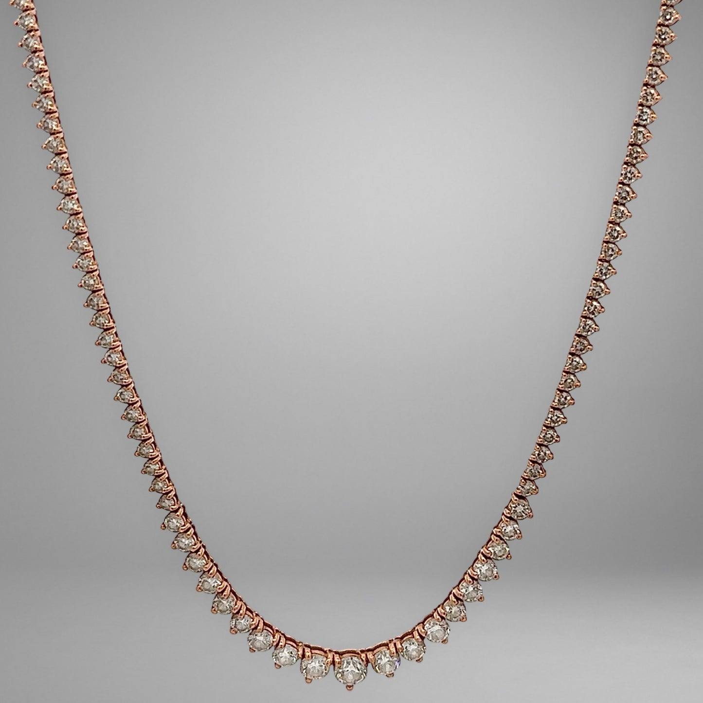 Rose gold necklace with diamonds on a gray background