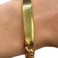 Gold bracelet on a wrist with a plain background