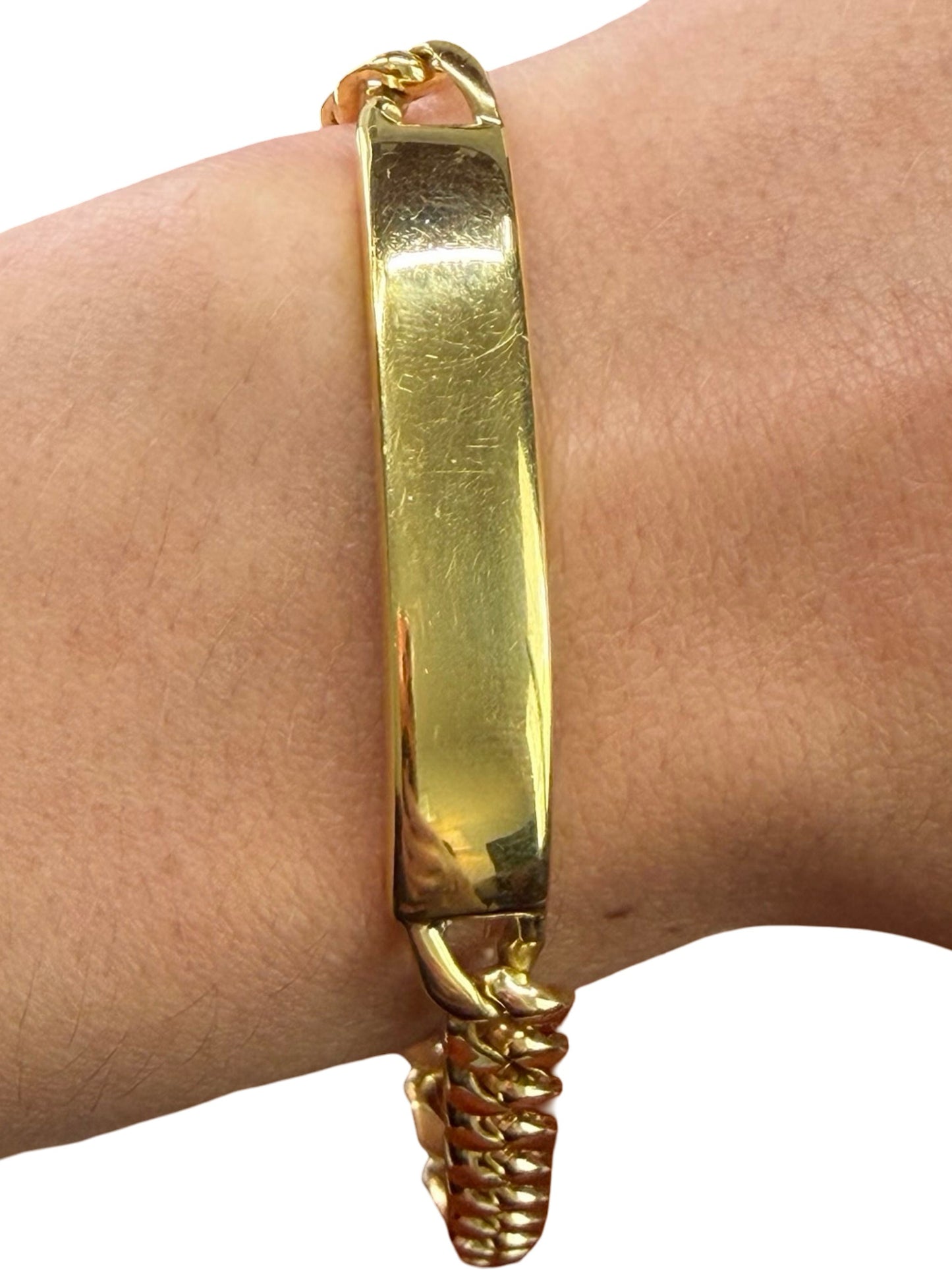 Gold bracelet on a wrist with a plain background