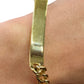 Gold bracelet on a wrist with a plain background