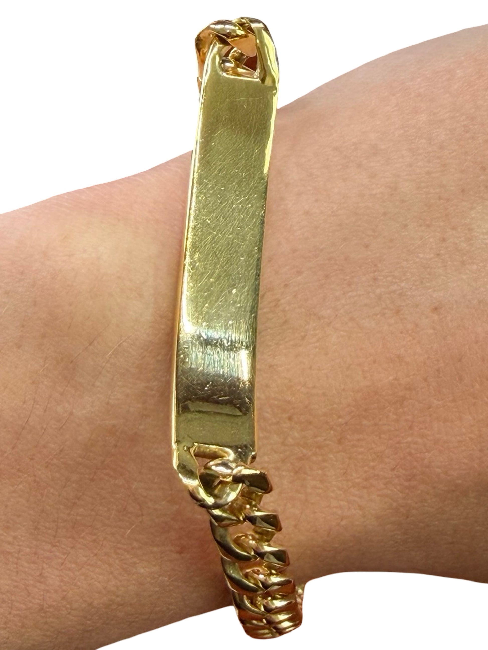 Gold bracelet on a wrist with a plain background