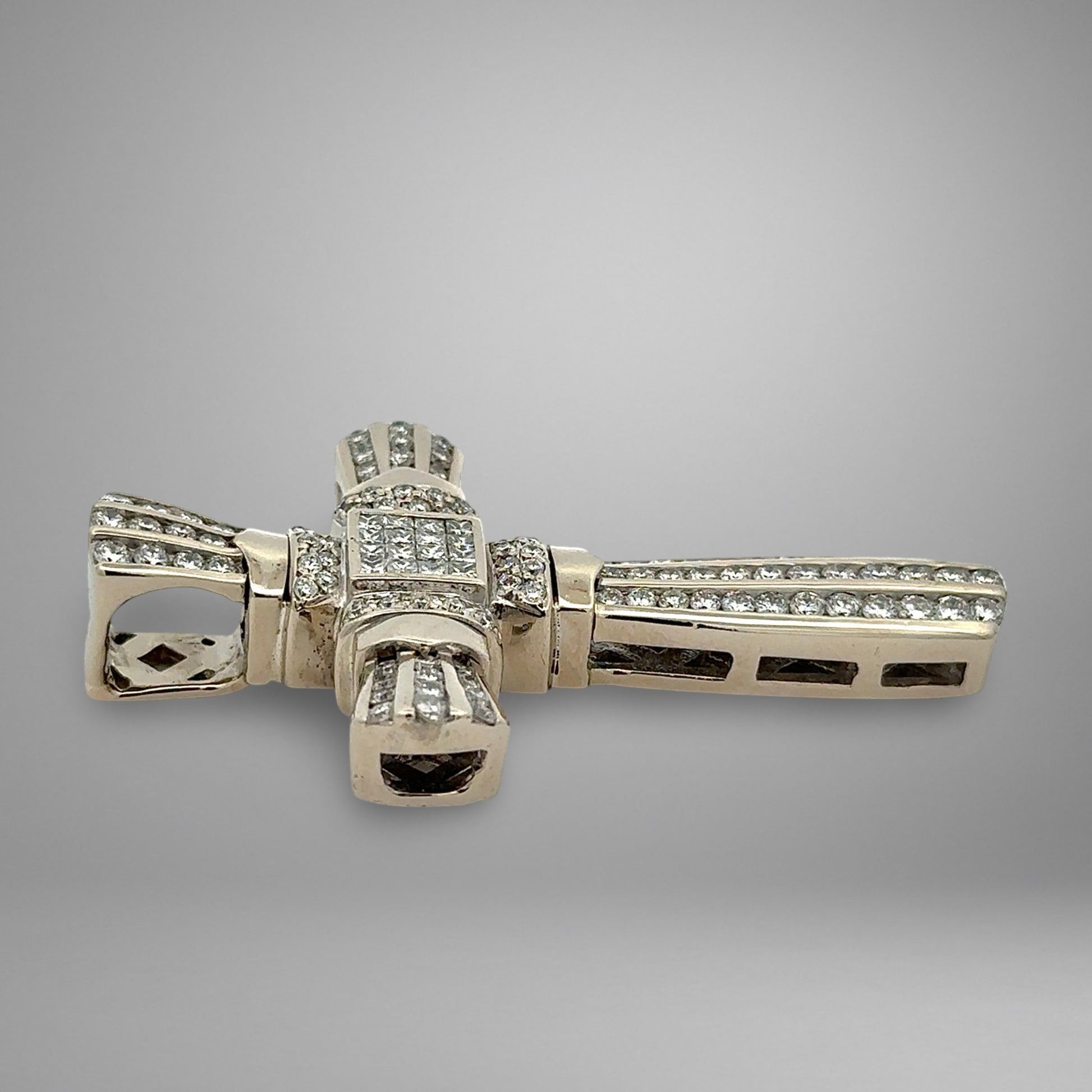 White gold cross pendant with diamonds on a gray background