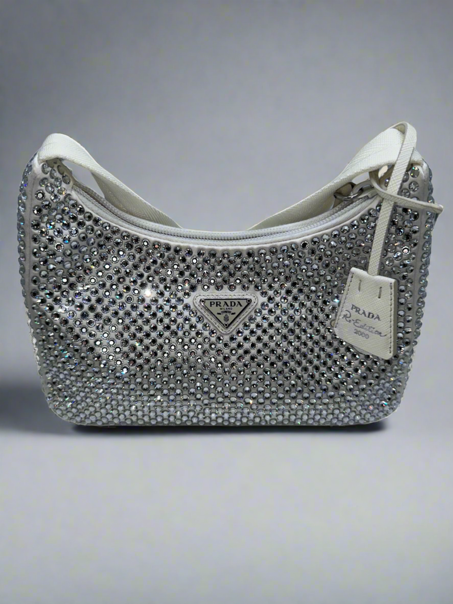 Pictured: The front of the Prada Crystal satin mini bag re-edition in white. It's a small white shoulder bag covered with crystals. No imperfections.