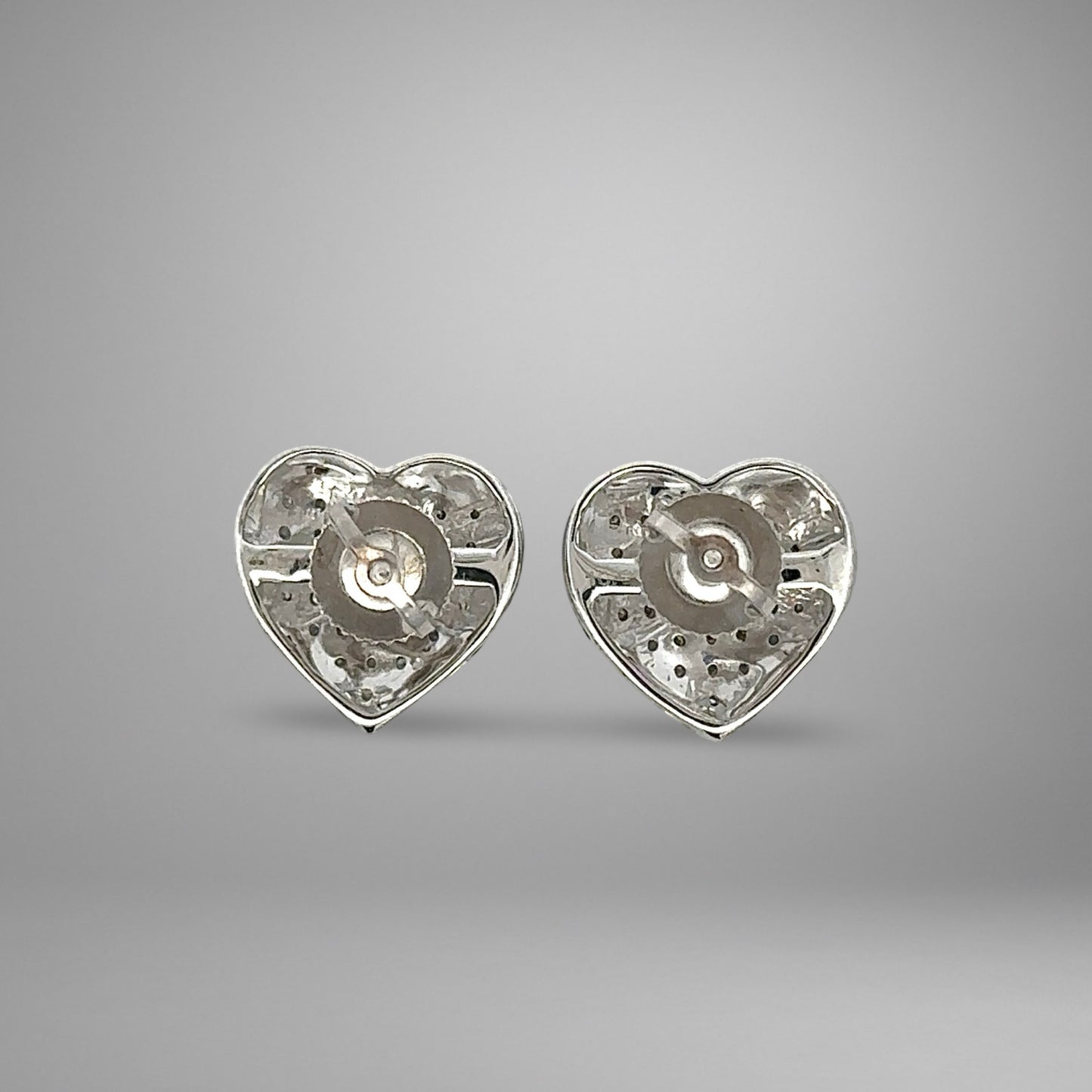 Heart-shaped white gold earrings on a gray background