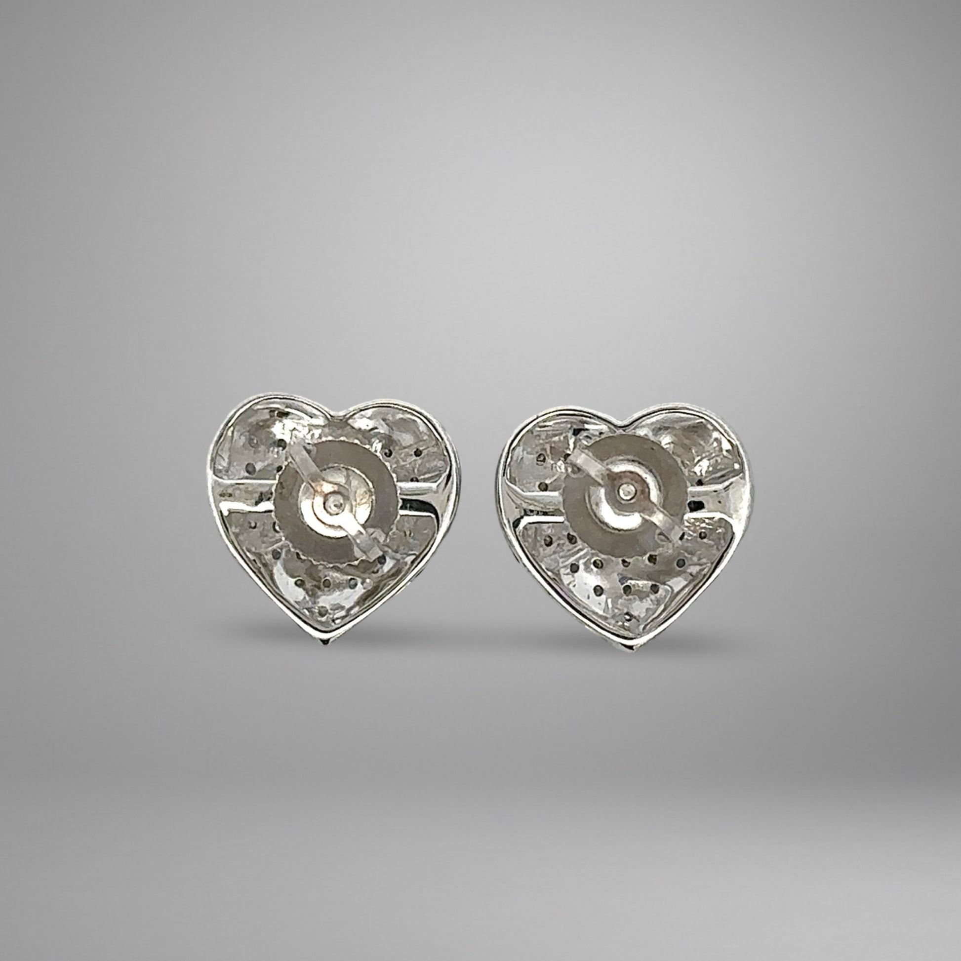 Heart-shaped white gold earrings on a gray background