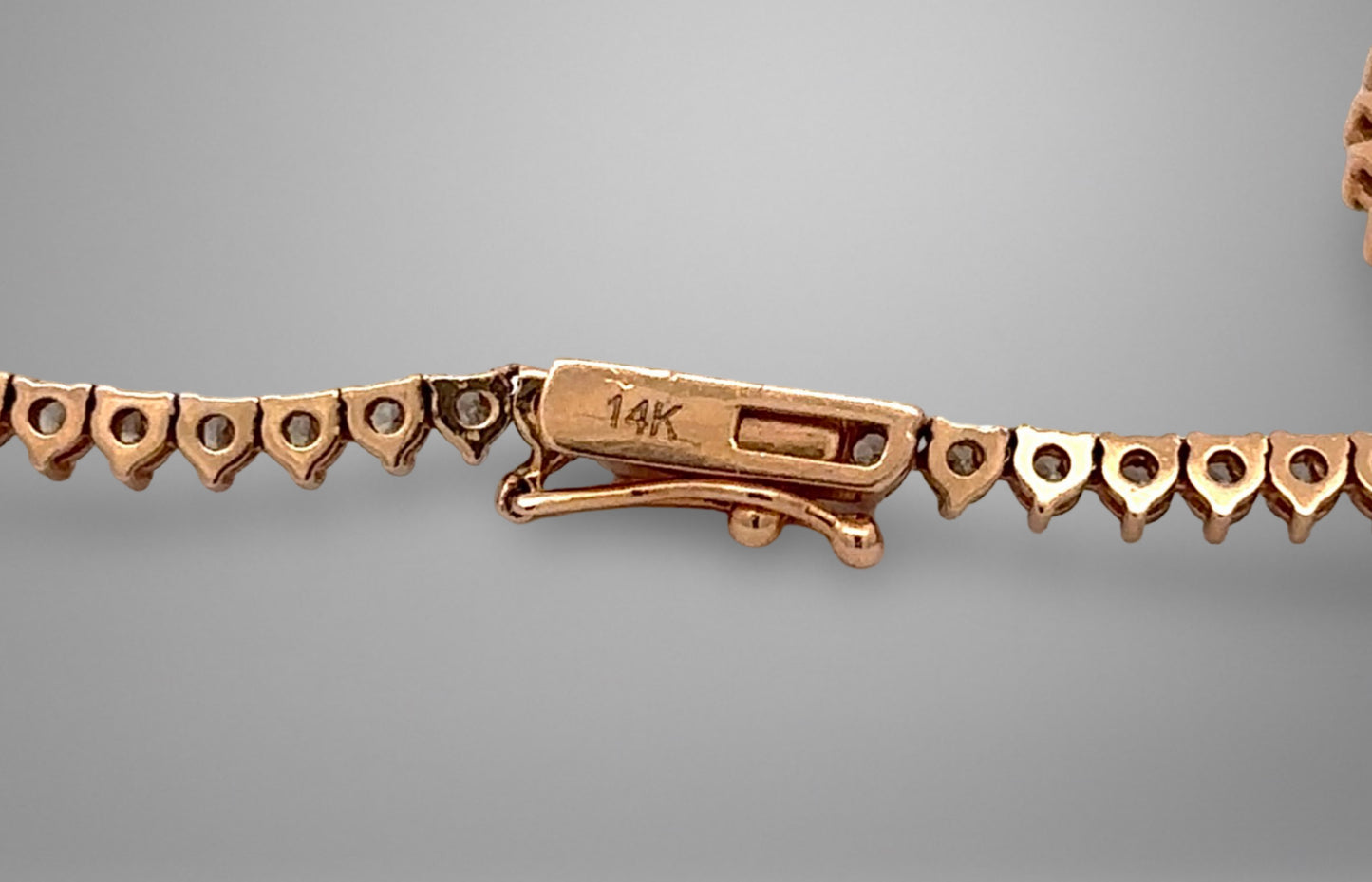 Close-up of a gold bracelet clasp on a gray background