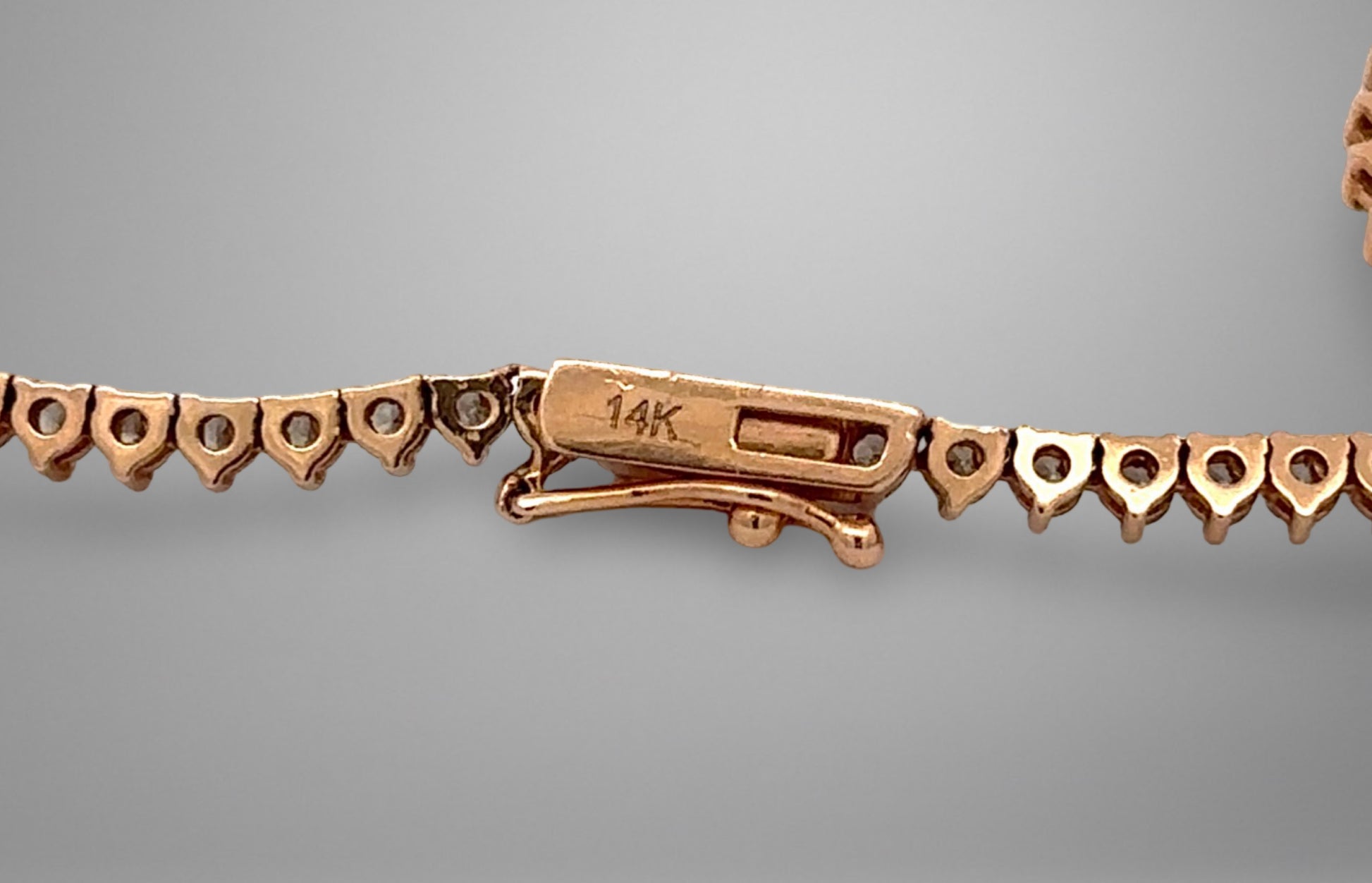 Close-up of a gold bracelet clasp on a gray background