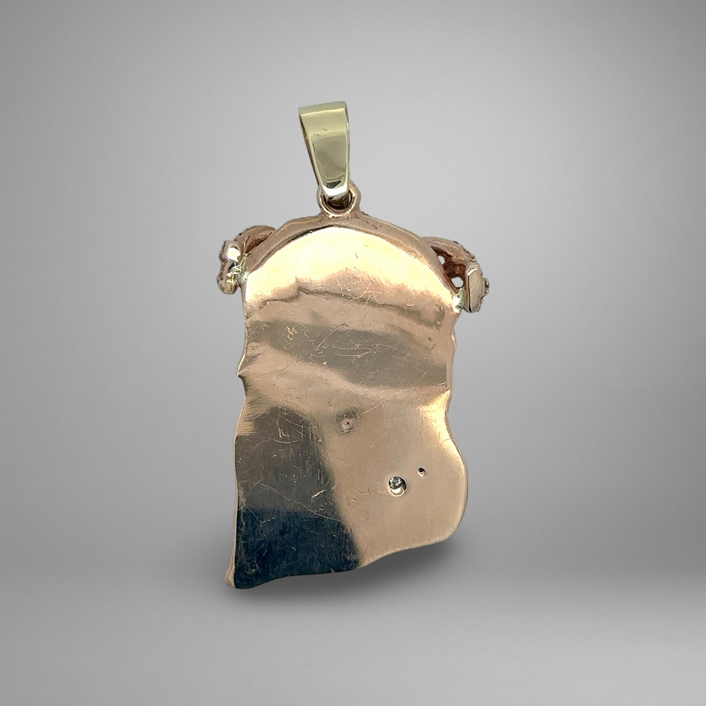 Back of pendant with scratches and tool marks on gold