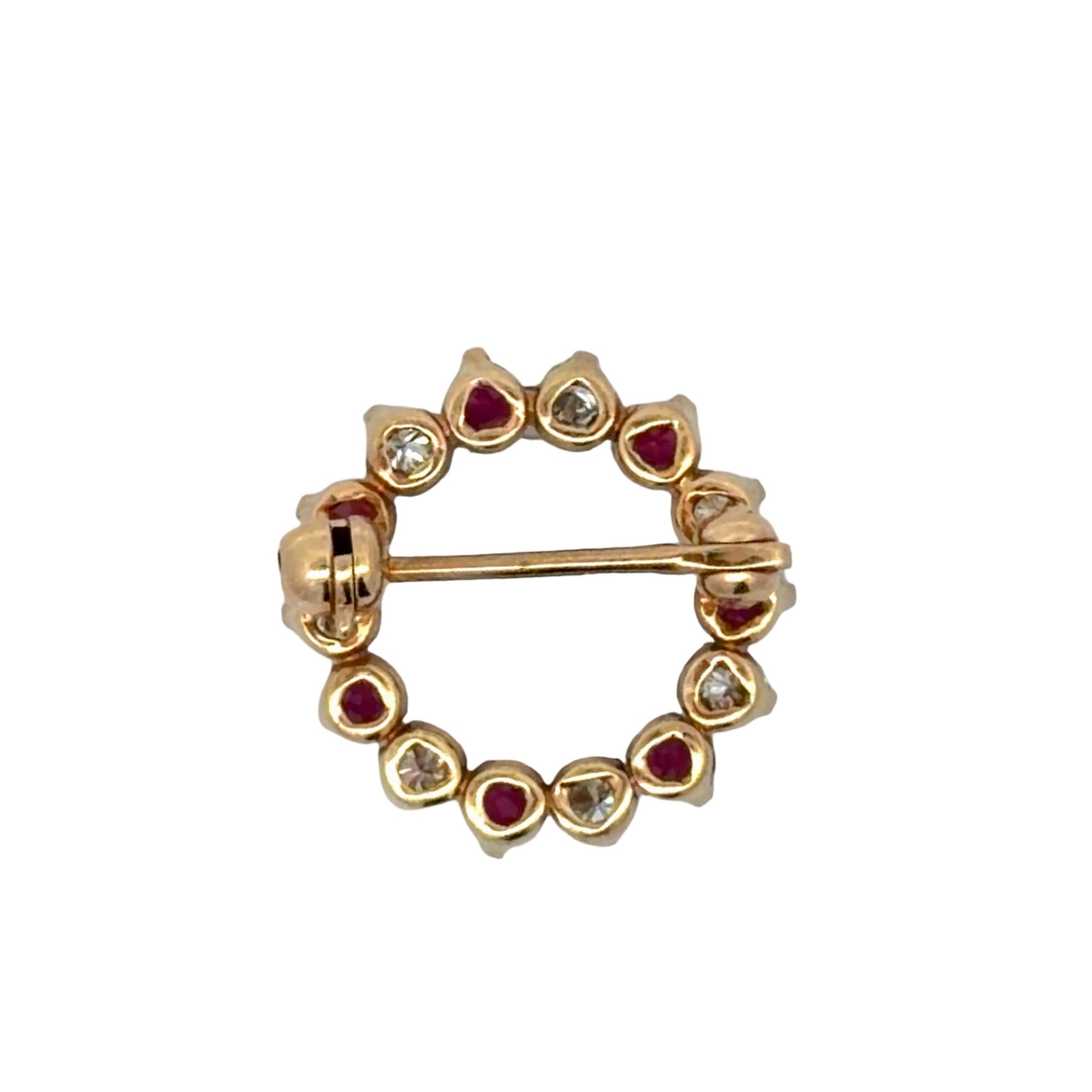 Gold brooch with red gemstones and diamonds on a white background
