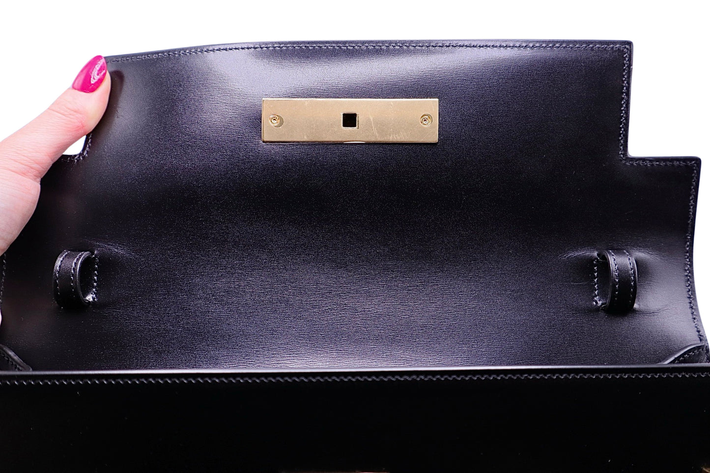 Inside flap of YSL black handbag with gold hardware + straps to hold the shoulder strap