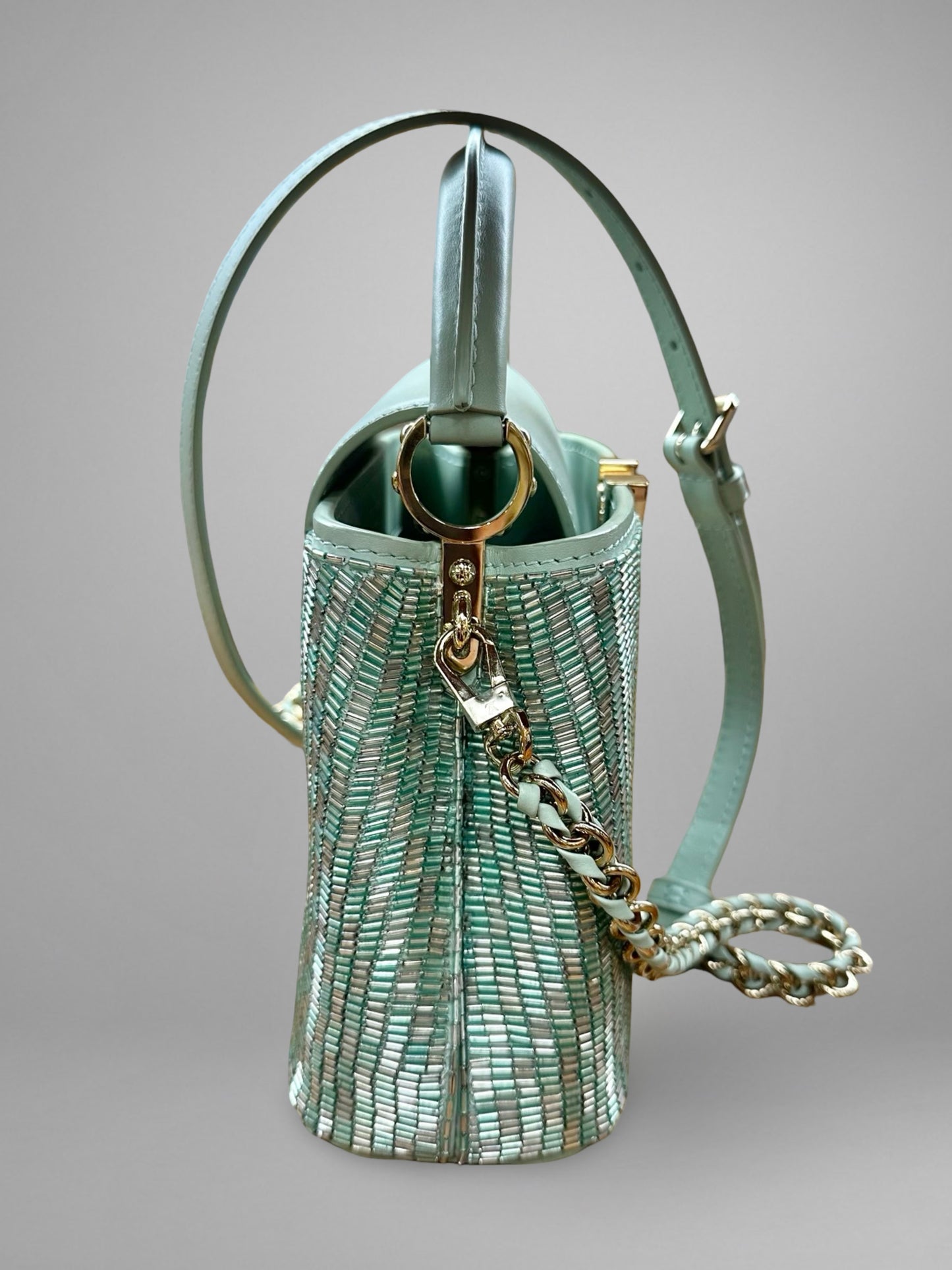 Green handbag with chain detail on a gray background
