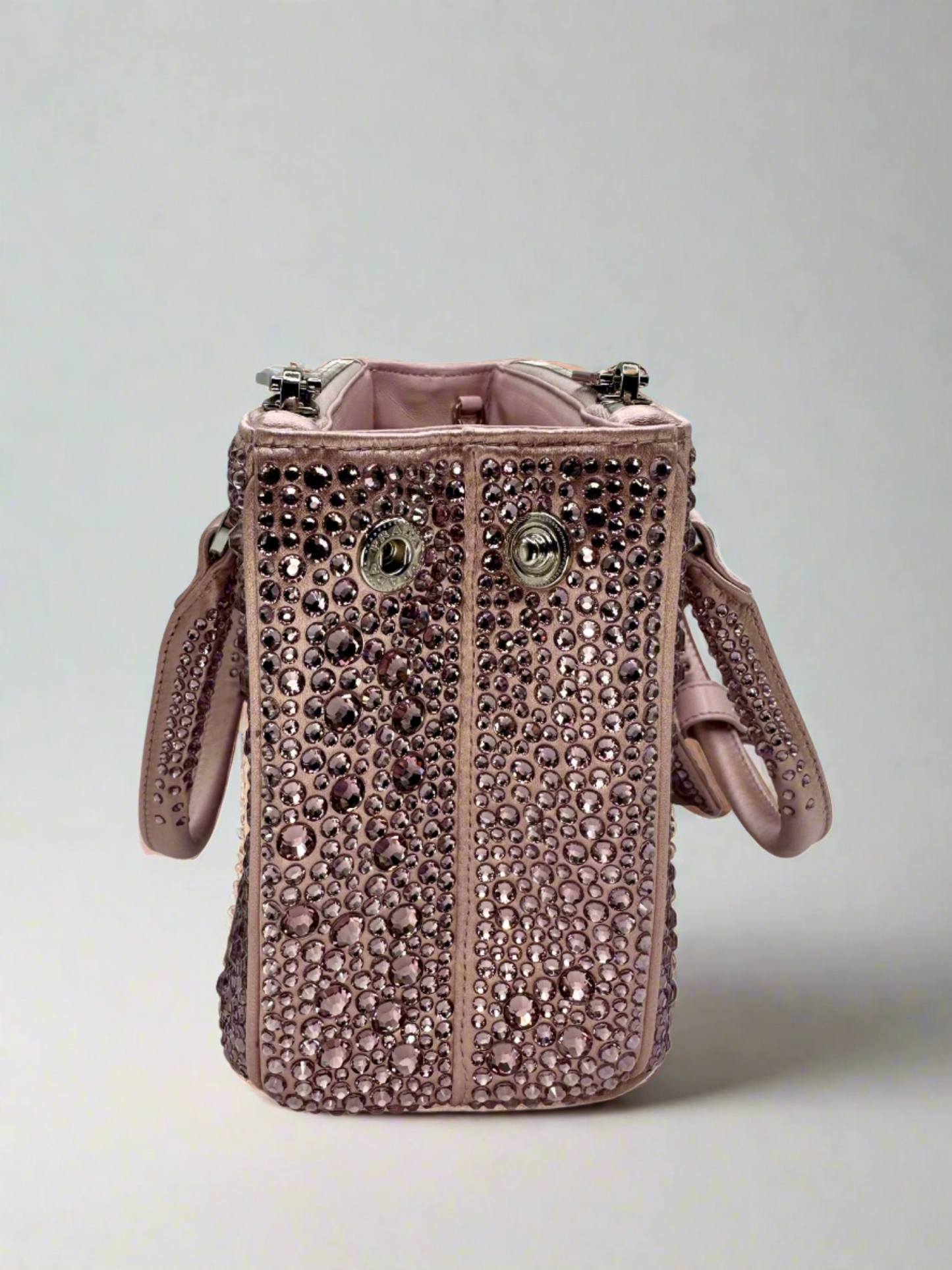 Pictured: The right side of the Prada Galleria Crystal mini satin bag in pink covered with pink crystals. It has 2 buttons on the side to close the bag. No imperfections.