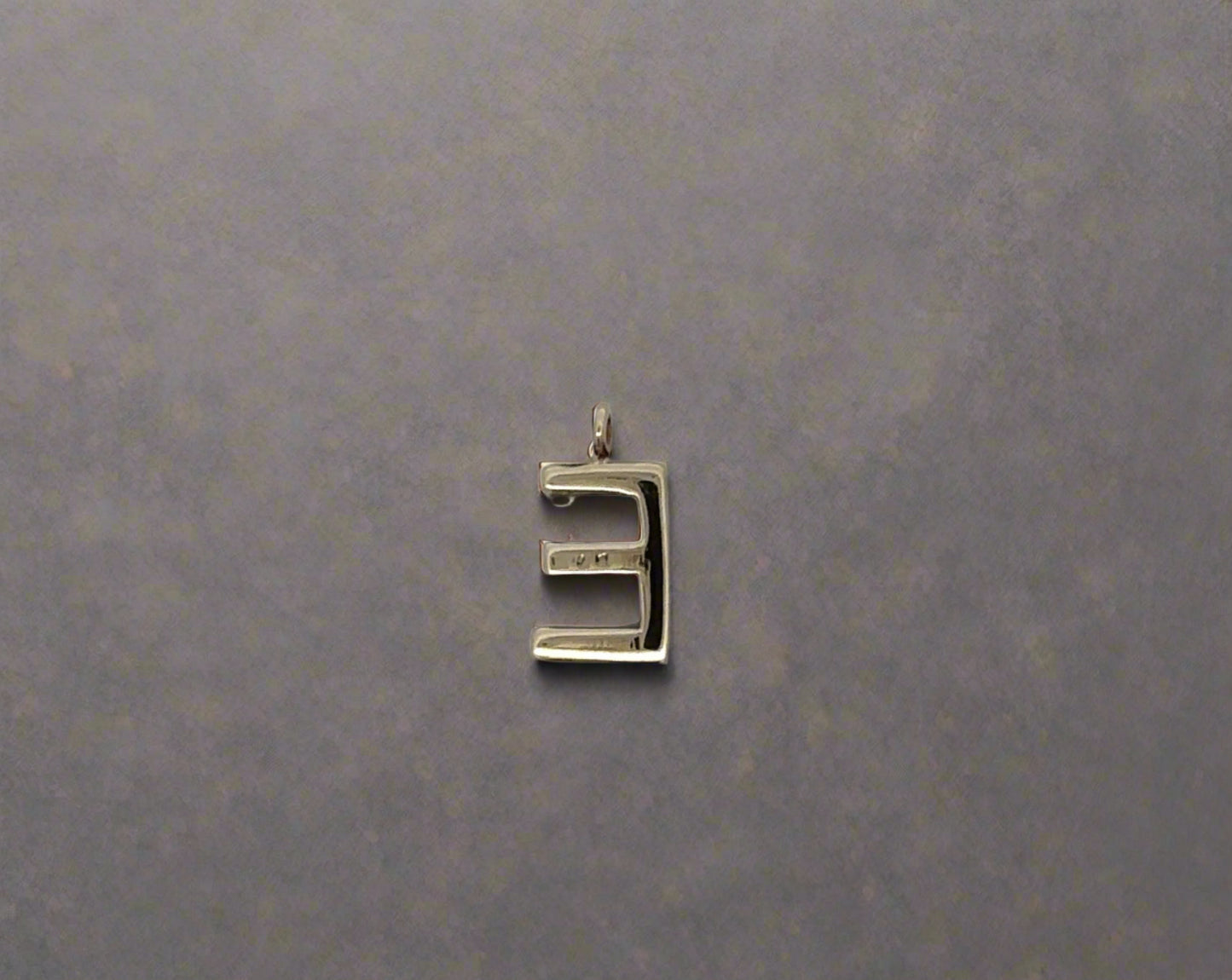 Back of E pendant with marks on back